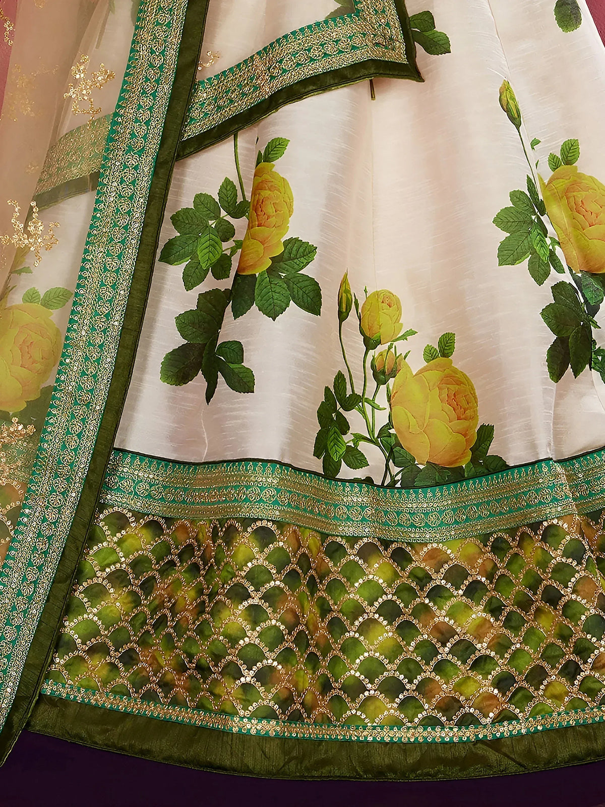 Detailed view of a white ethnic lehenga with yellow floral prints and green embroidered borders.