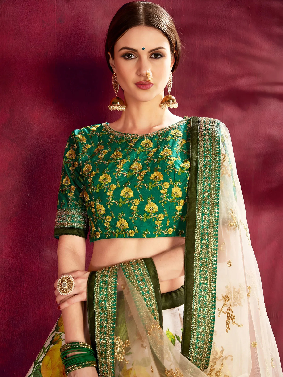 Woman wearing a green floral embroidered blouse and white lehenga choli with a dupatta