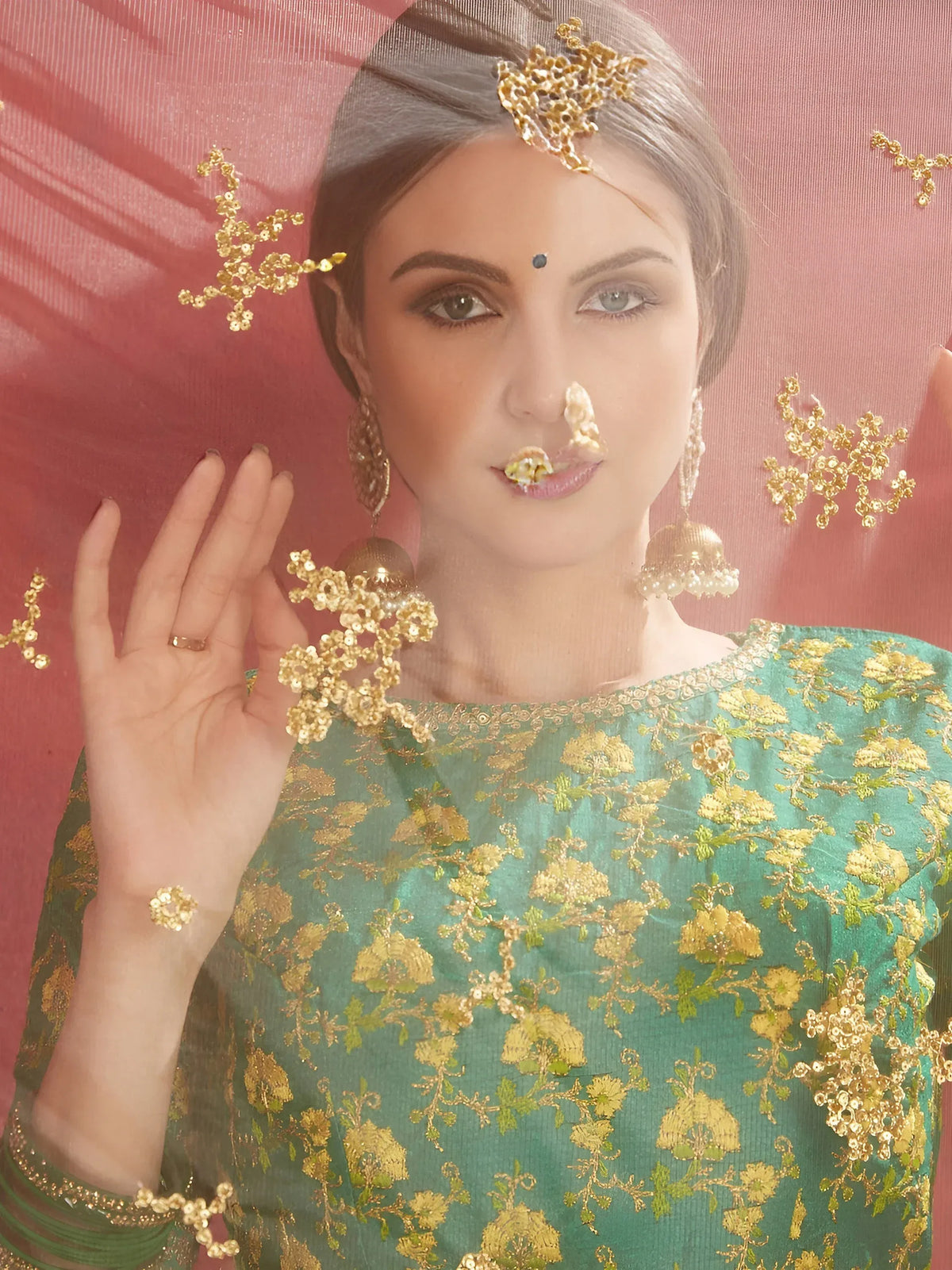 Woman wearing a green gold embroidered ethnic outfit and traditional Indian jewelry