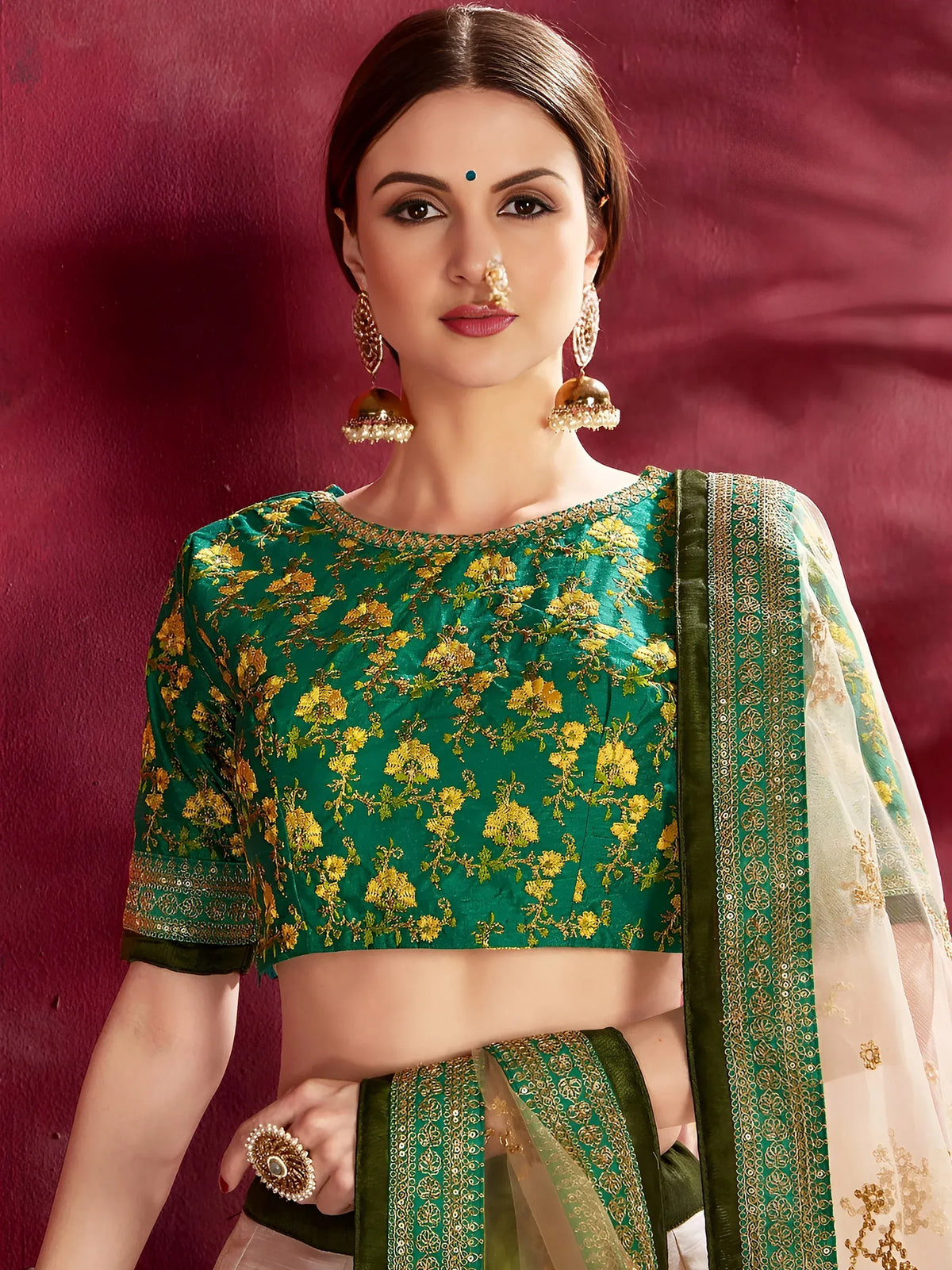 Woman wearing a green floral embroidered designer lehenga choli with a beige dupatta.