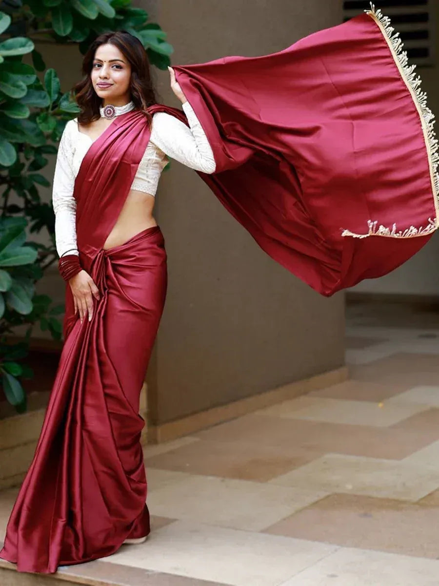 Woman in maroon satin saree with gold fringe, paired with white blouse, showcasing elegant ethnic wear