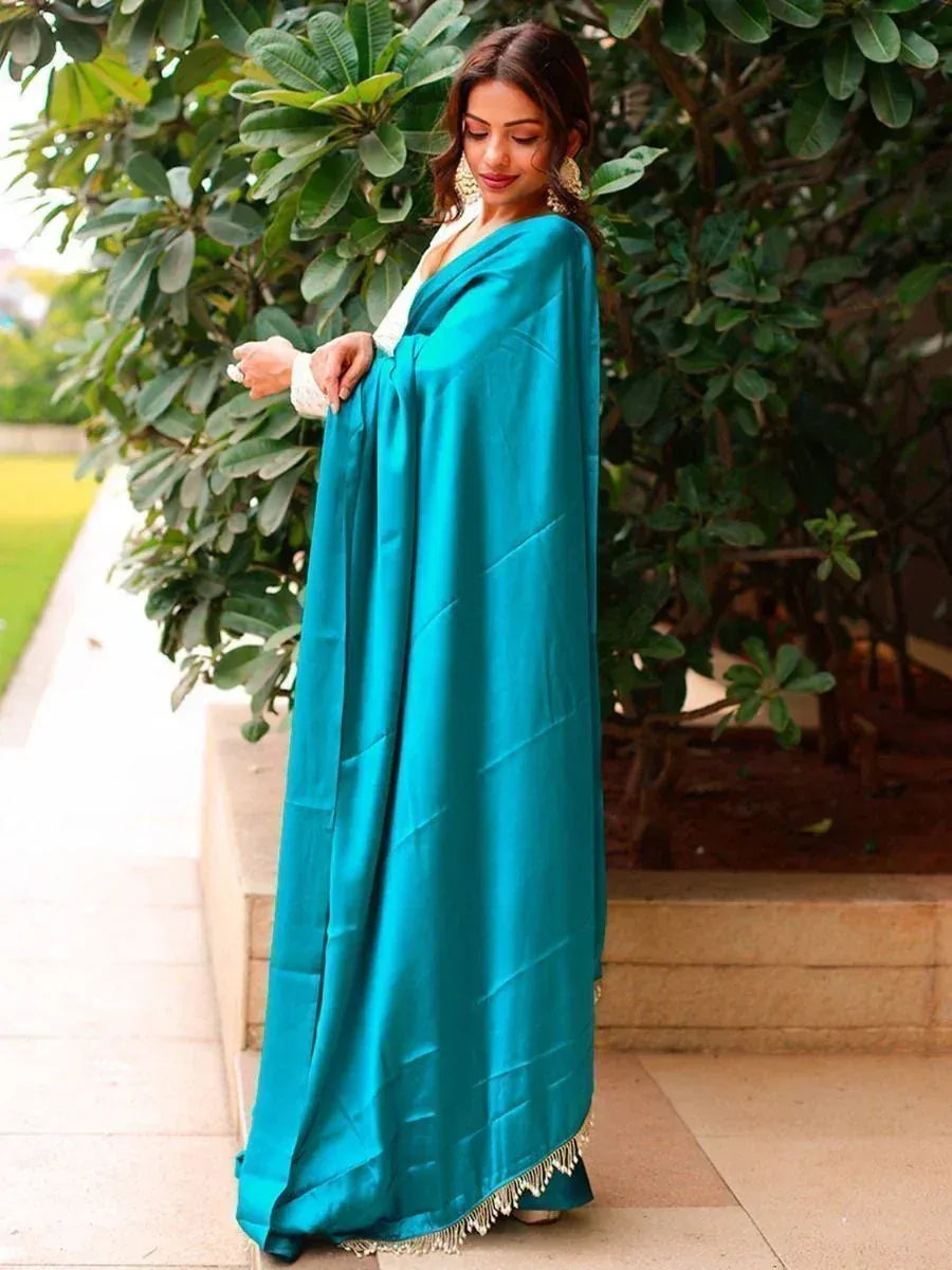 Teal satin ethnic gown with white lace and gold fringe, styled with statement earrings outdoors