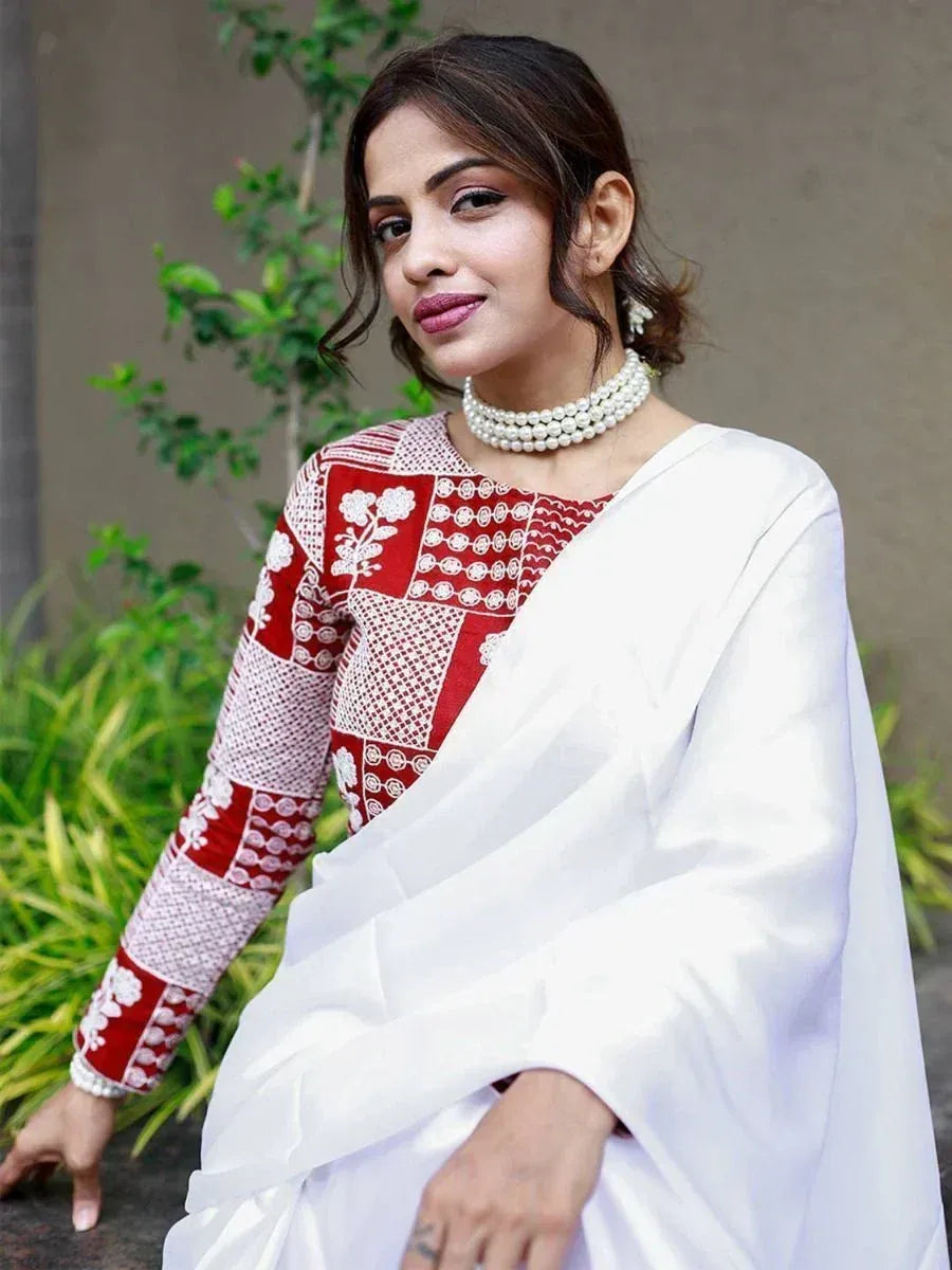 Woman in red and white embroidered ethnic saree with pearl necklace, perfect for Indian occasions