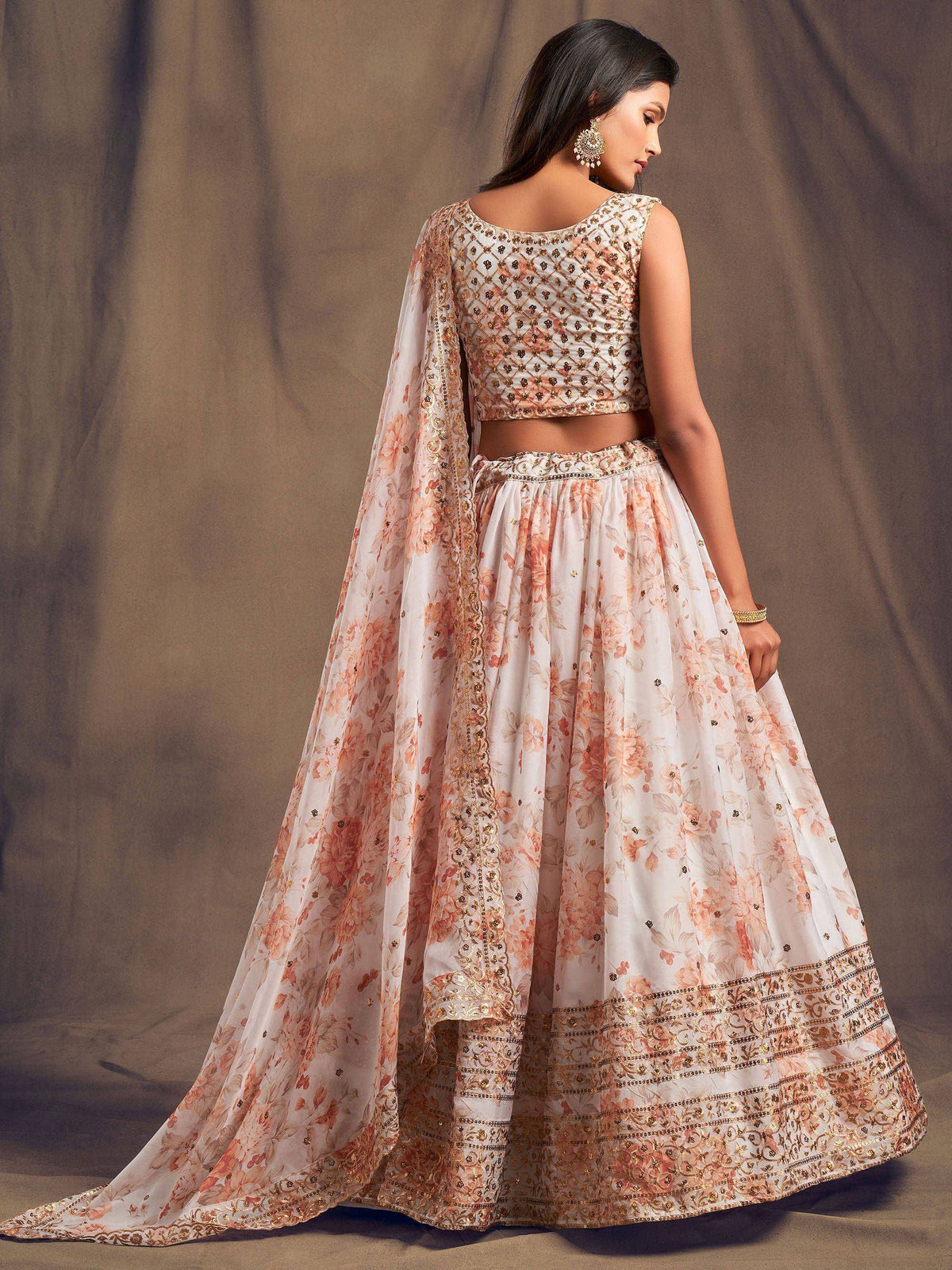 Elegant white and peach floral lehenga choli with gold embroidery and cape, perfect for Indian weddings or festive occasions.