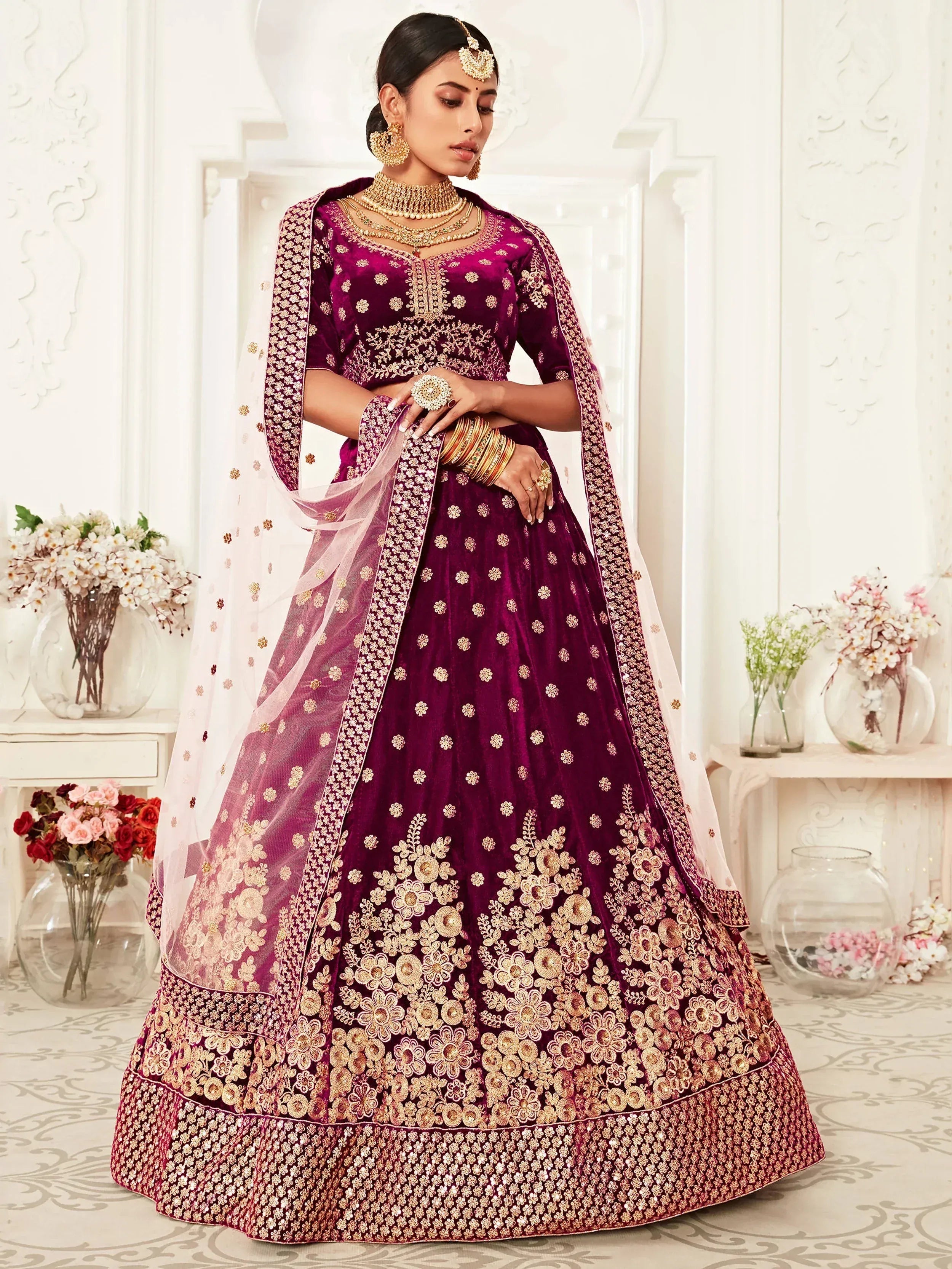 Elegant maroon velvet lehenga choli with gold floral embroidery, perfect for Indian weddings and festive occasions.