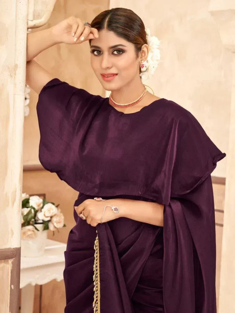Woman in elegant purple ethnic gown with cape sleeves, floral hair accessory, and traditional jewelry