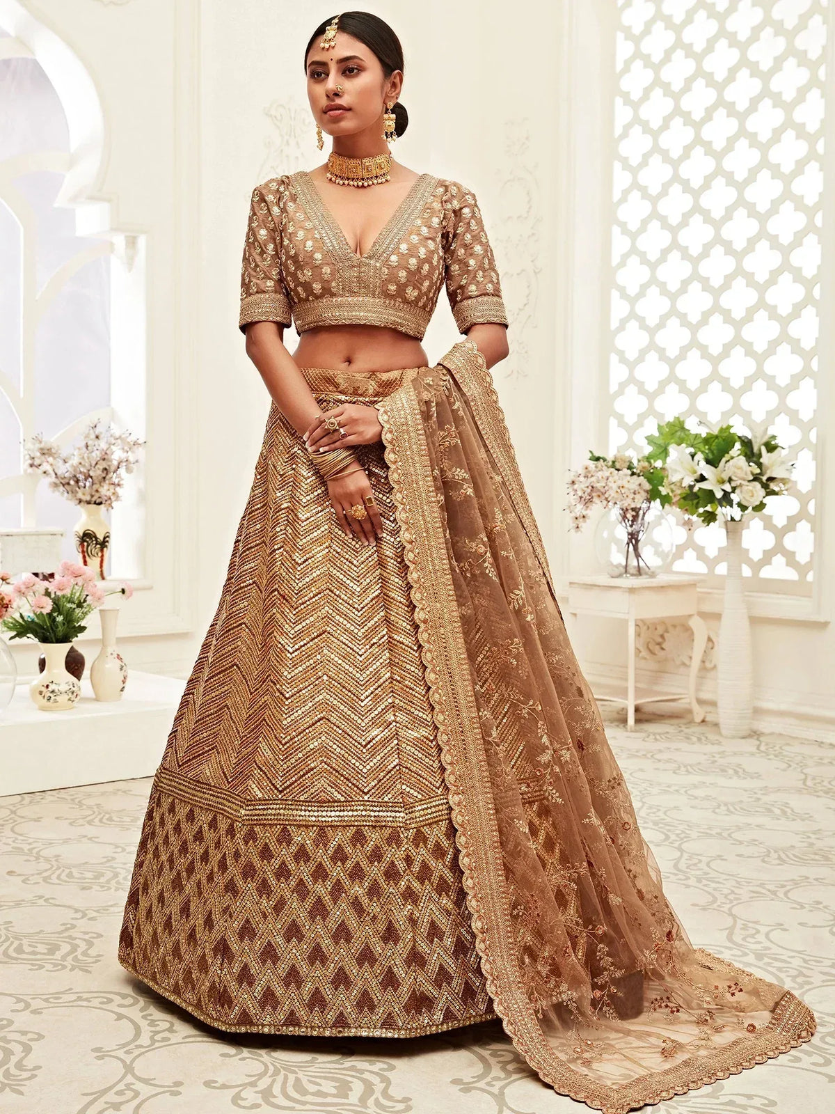 Woman in a gold sequined designer lehenga choli with matching dupatta.