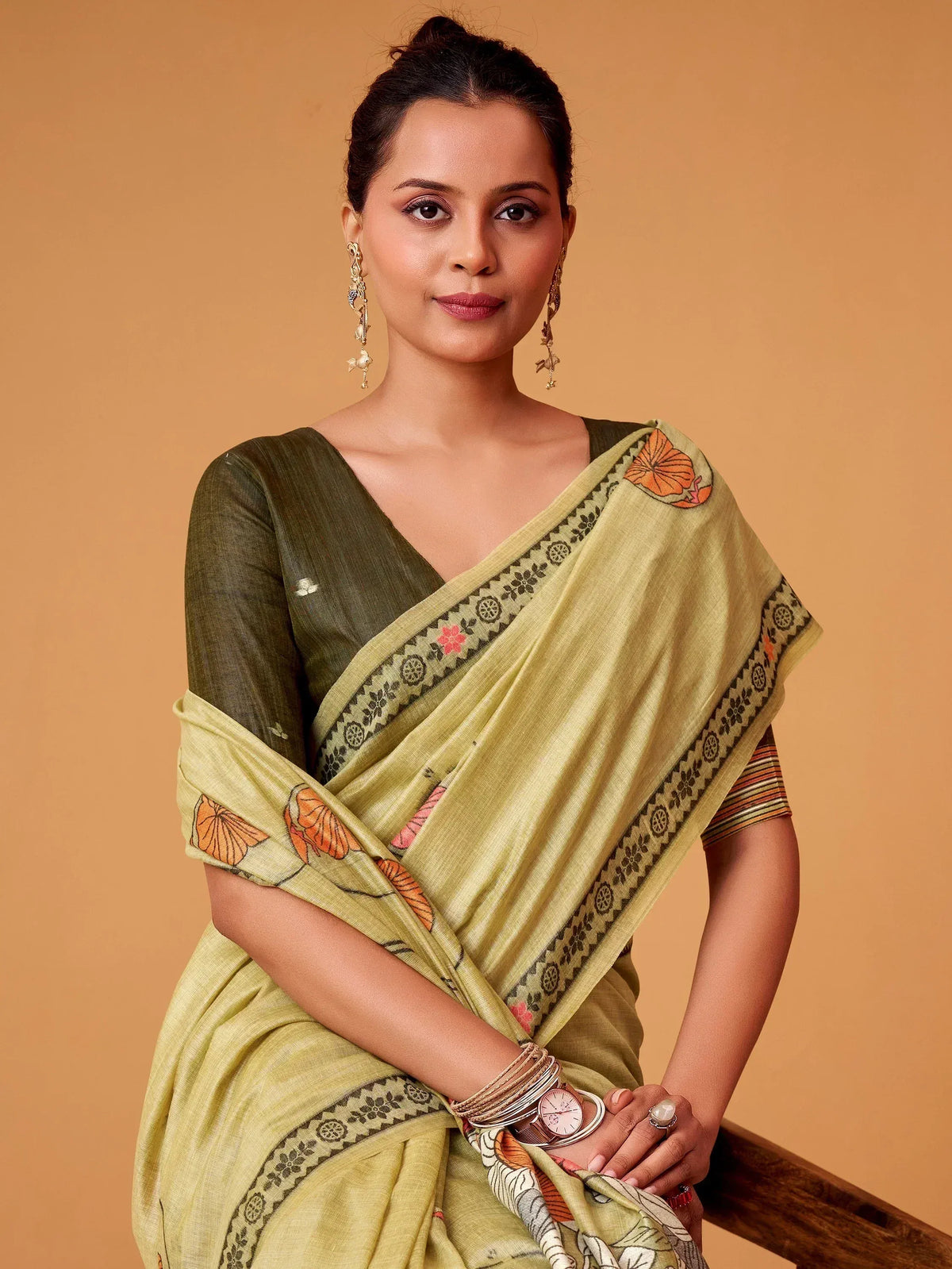 Woman in olive green saree with floral border, styled with ethnic jewelry for Indian ethnic wear