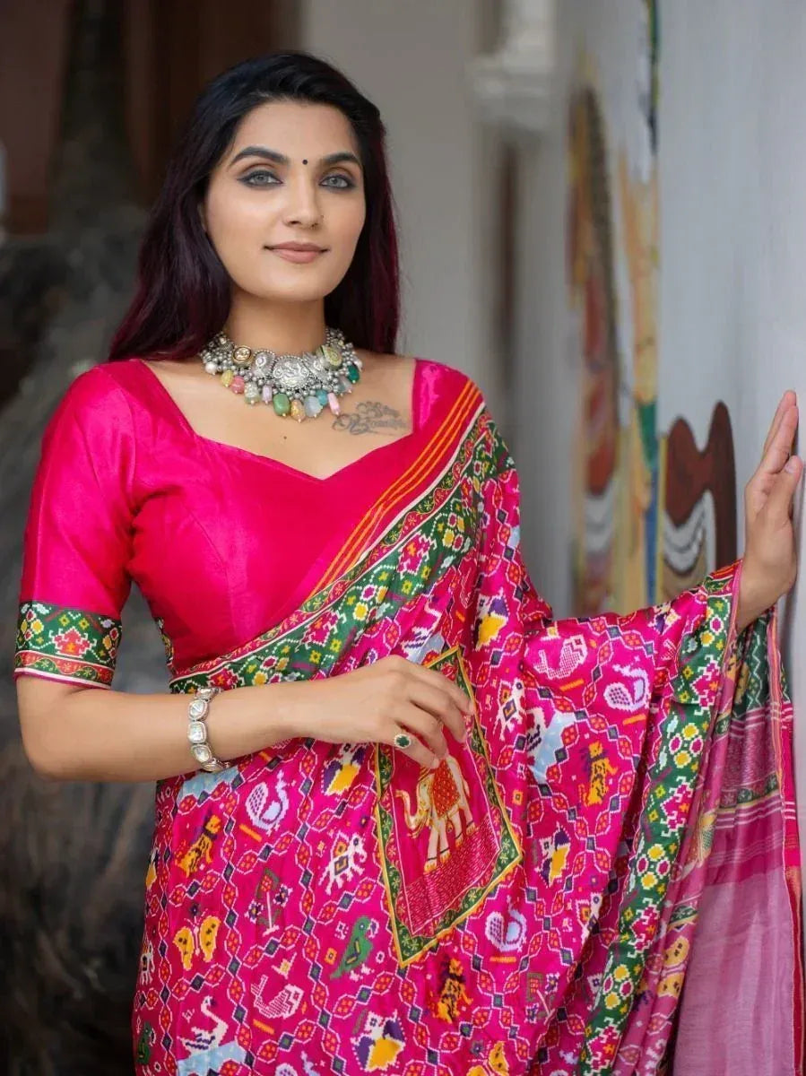 Woman in vibrant pink printed saree with elephant motifs, ethnic jewelry, and designer blouse