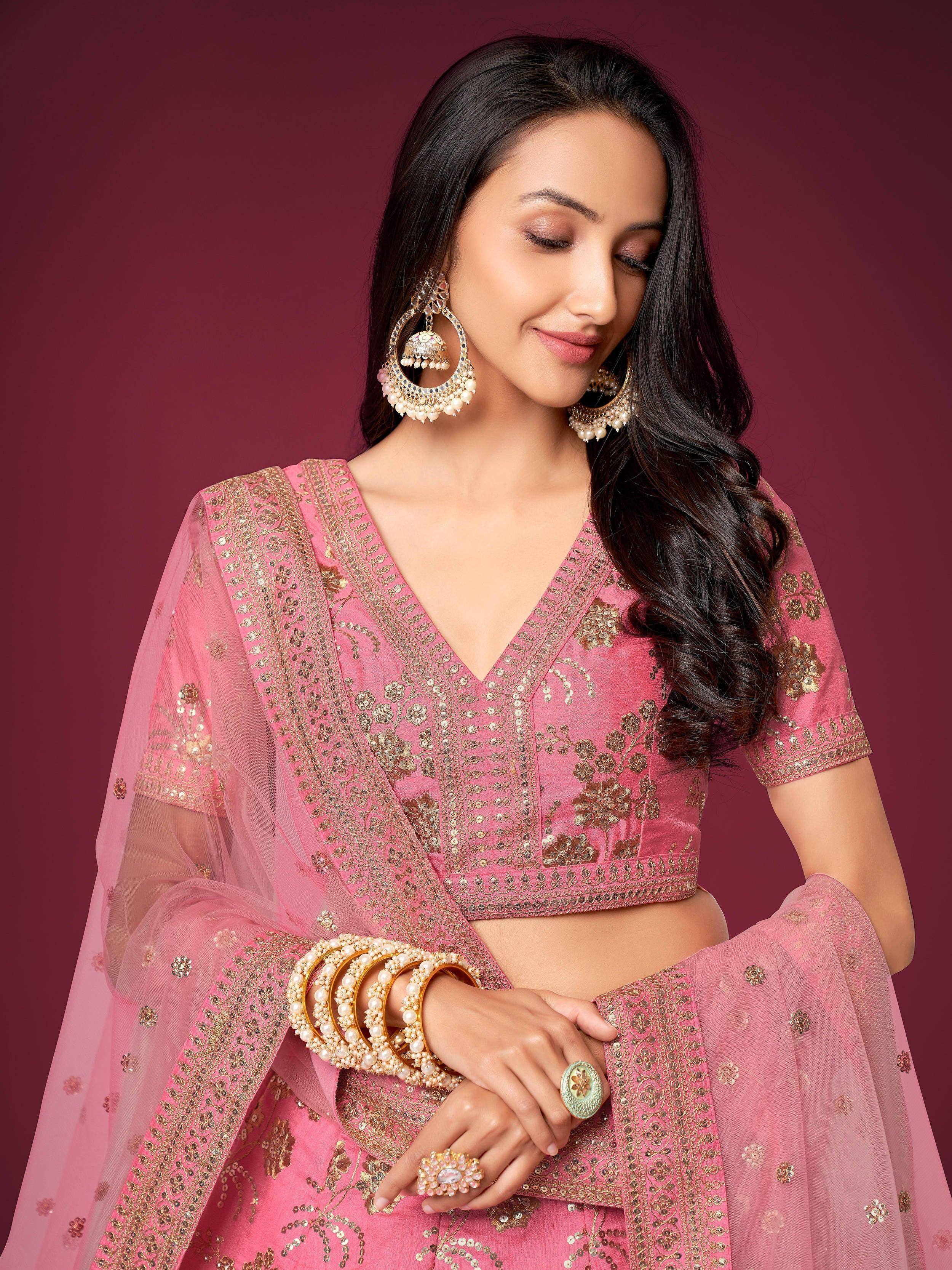Pink embroidered lehenga choli with gold detailing and matching jewelry for Indian ethnic wear