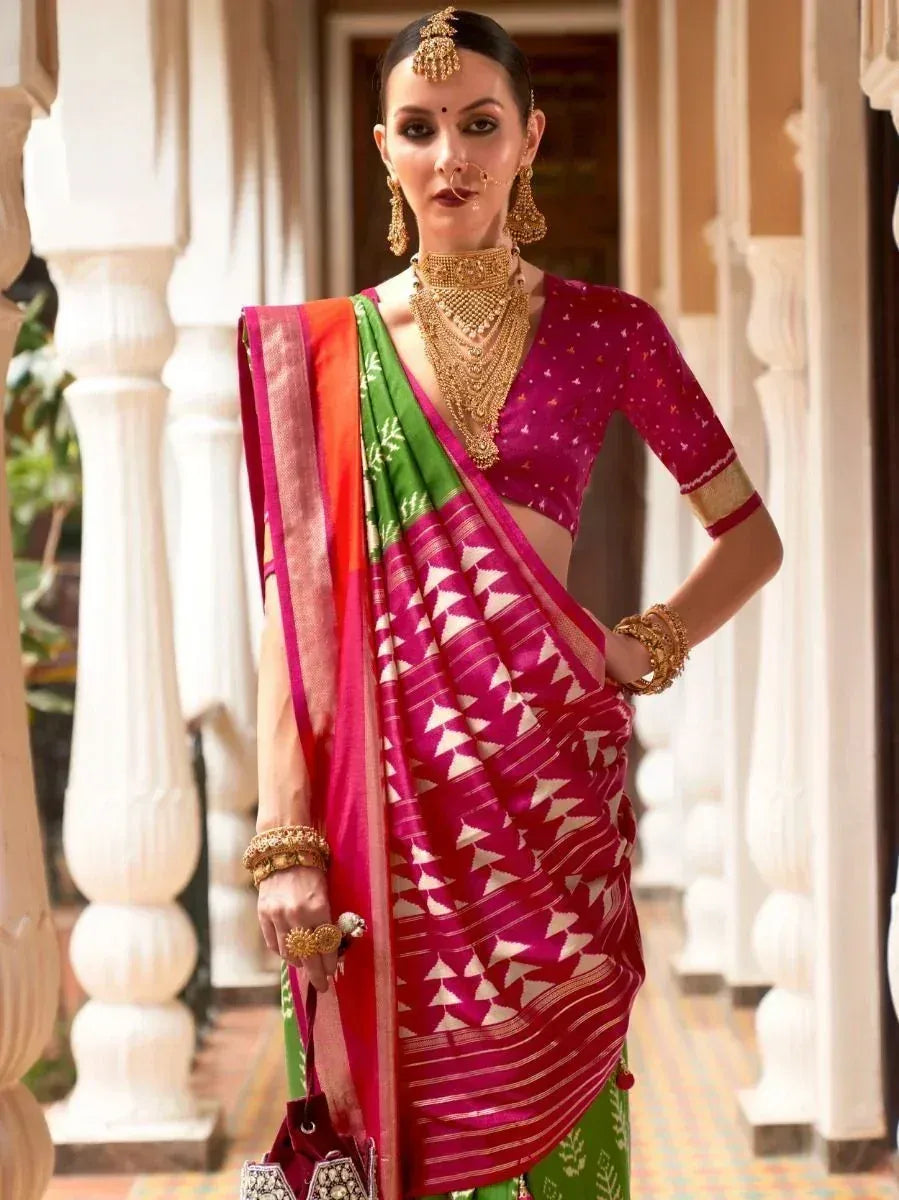 Woman in vibrant pink and green ethnic saree with gold jewelry, traditional Indian attire