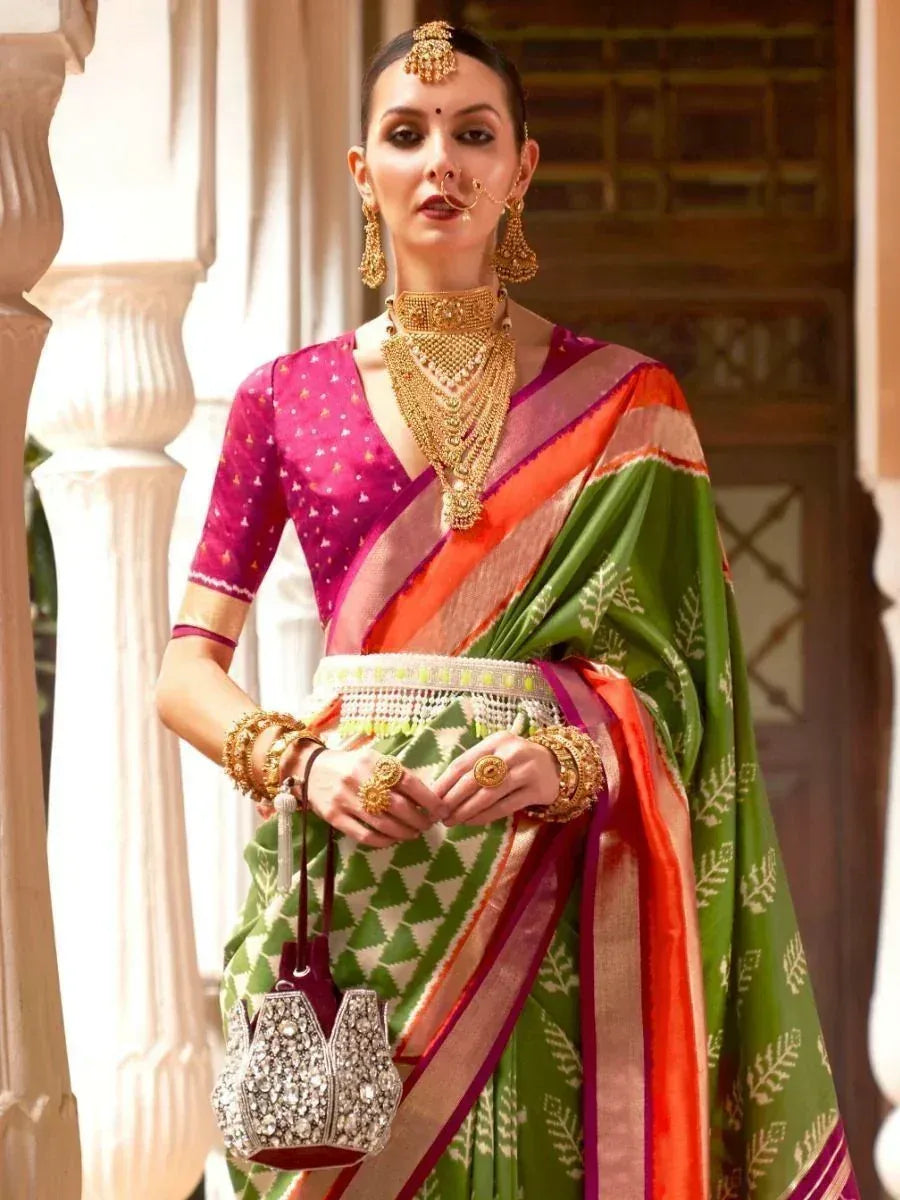 Woman in vibrant green and pink ethnic saree with gold jewelry, traditional Indian wear