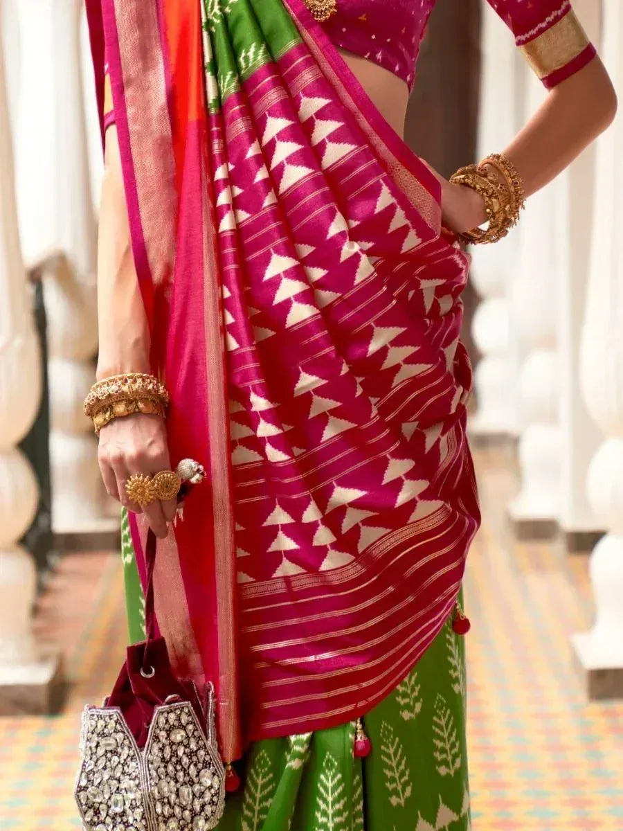 Vibrant pink and green ethnic saree with geometric print, gold jewelry, and embellished clutch for Indian occasions