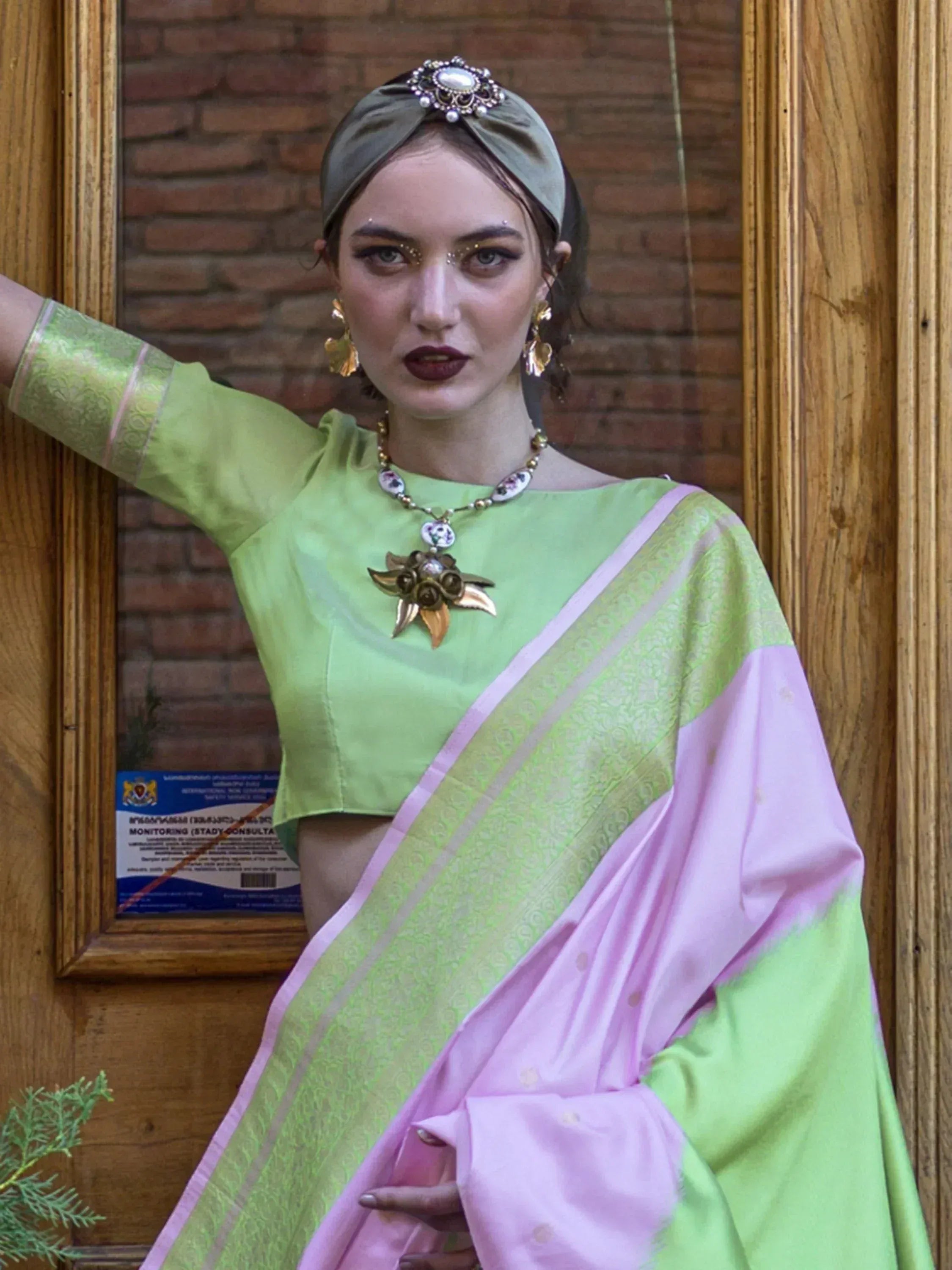 Woman in green and pink designer saree with gold jewelry and headpiece, ethnic Indian wear