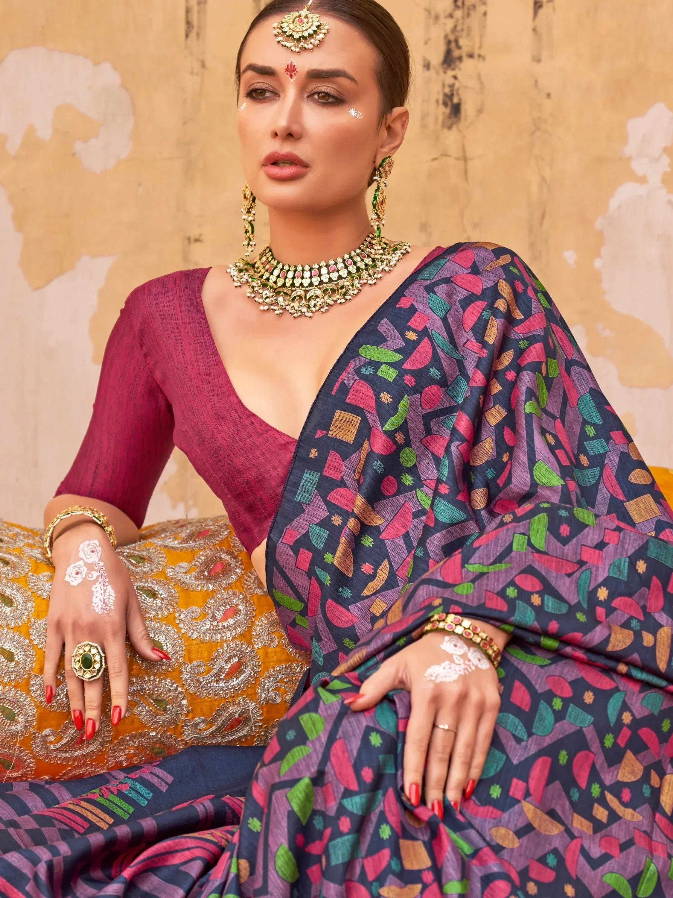 Woman in vibrant geometric print saree with maroon blouse, traditional jewelry, and henna designs