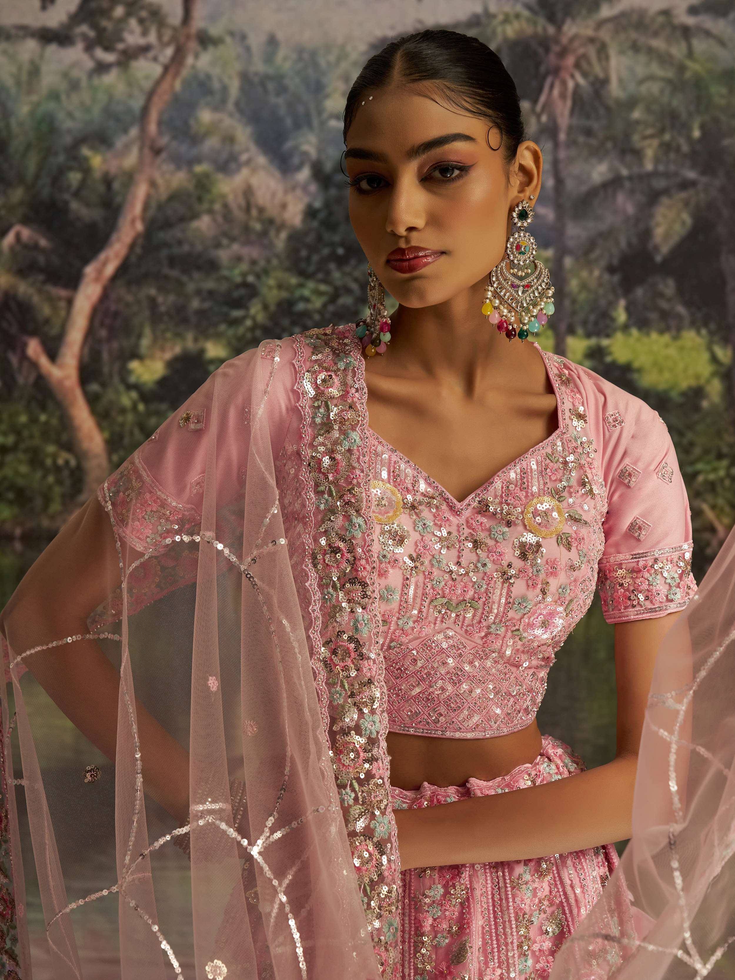 Pink embroidered lehenga choli with sequins and floral motifs, paired with statement earrings for Indian ethnic wear
