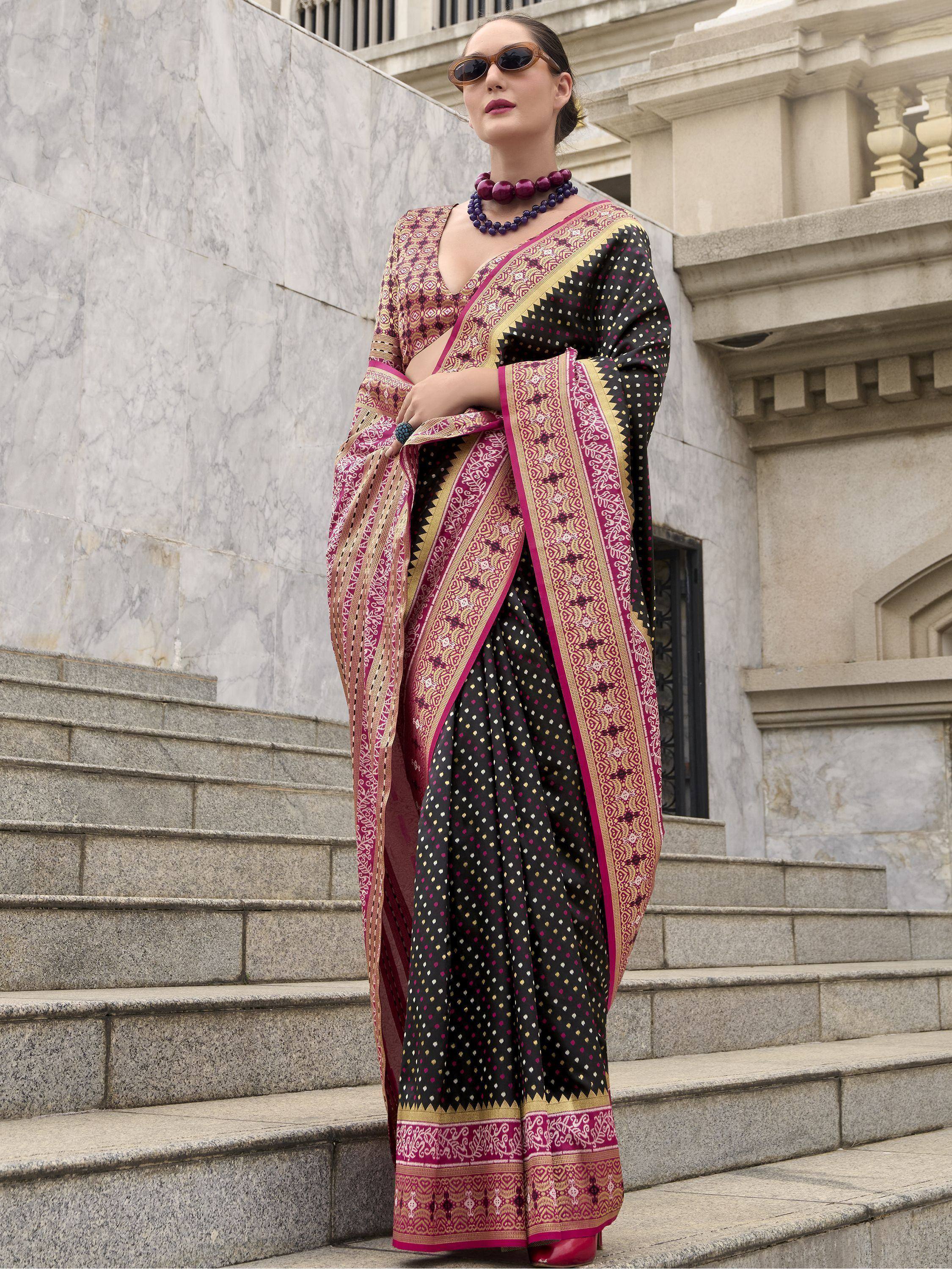 Stylish black and pink ethnic saree with gold border, worn on marble steps