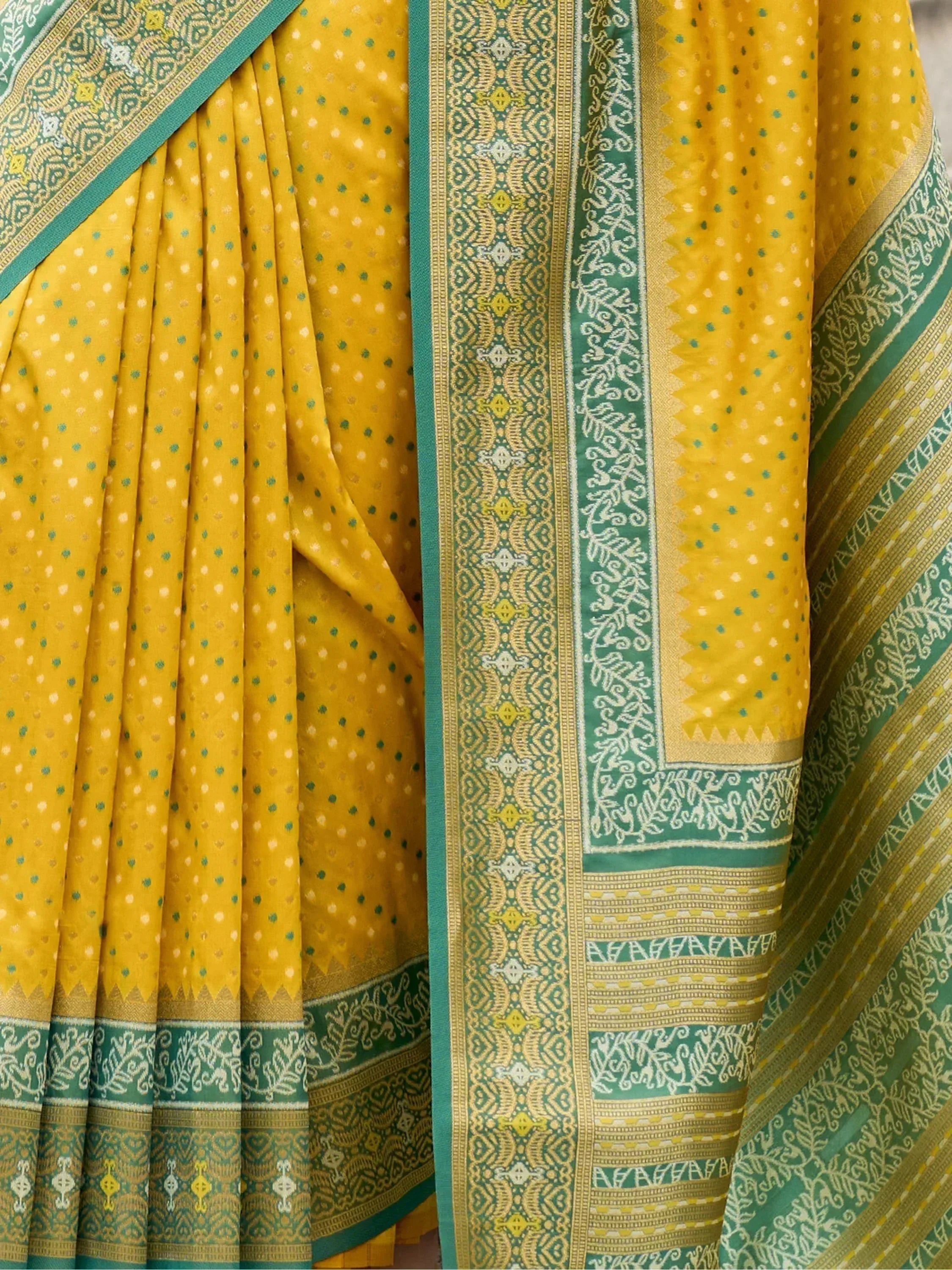 Yellow and green ethnic saree with intricate border patterns and dotted design