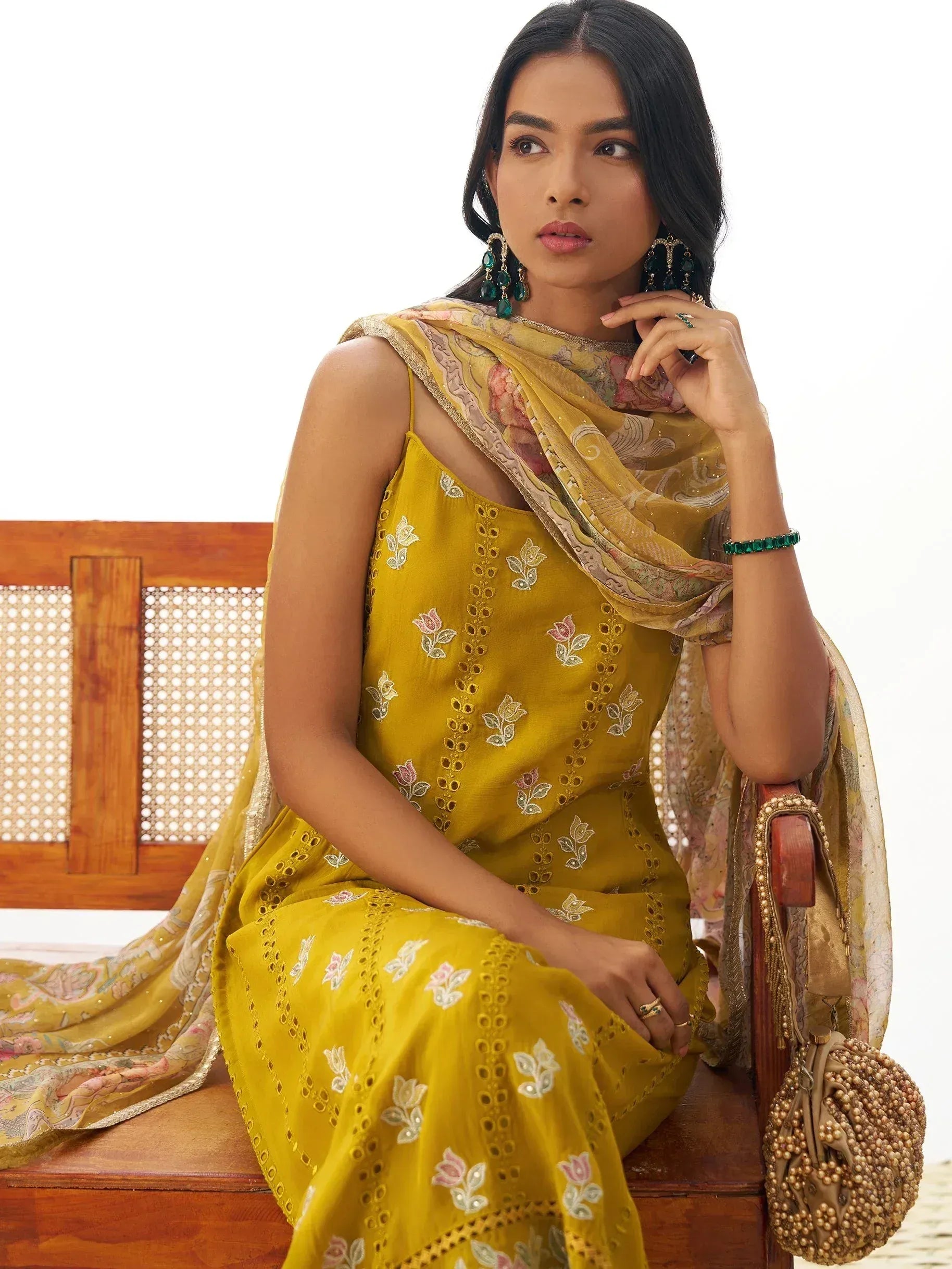 Yellow embroidered ethnic gown with floral dupatta, styled with green jewelry for Indian occasions