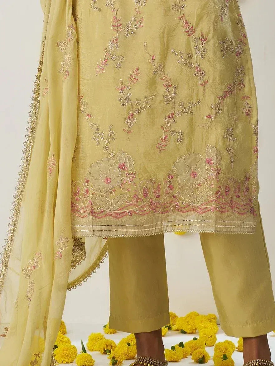 Yellow embroidered salwar kameez with floral detailing and matching dupatta, styled with marigold flowers.