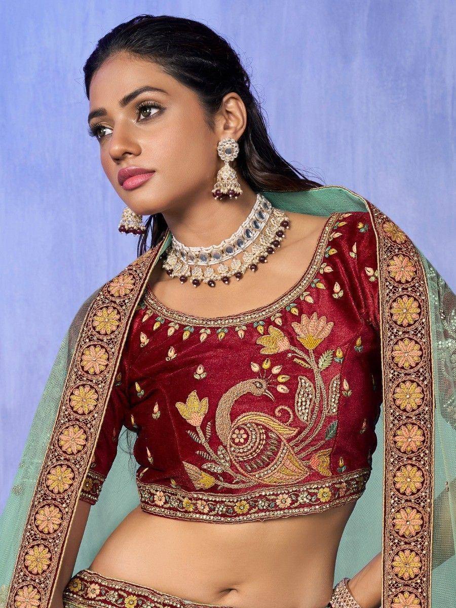 Maroon embroidered lehenga choli with peacock design, paired with green dupatta and traditional jewelry