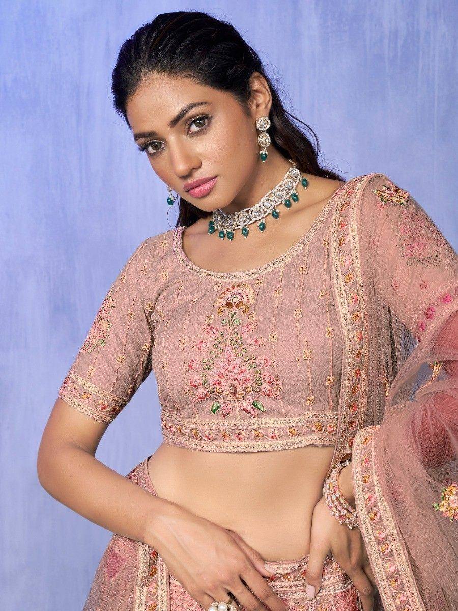 Pink embroidered lehenga choli with floral detailing and green stone jewelry, ideal for Indian ethnic wear
