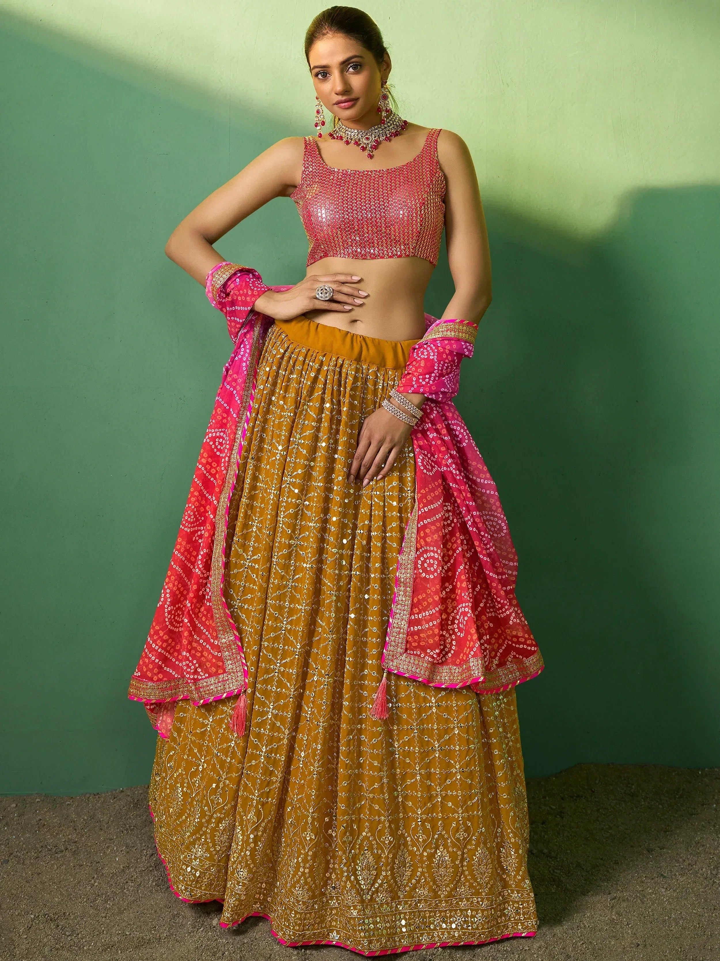 Elegant Indian lehenga choli with golden skirt and pink sequined blouse, perfect for festive occasions.