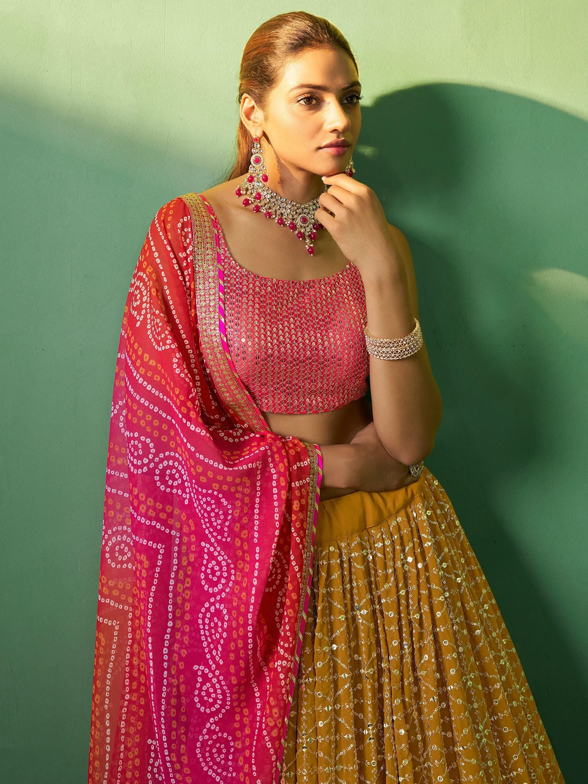 Woman in vibrant pink and gold lehenga choli with patterned dupatta, traditional Indian ethnic wear