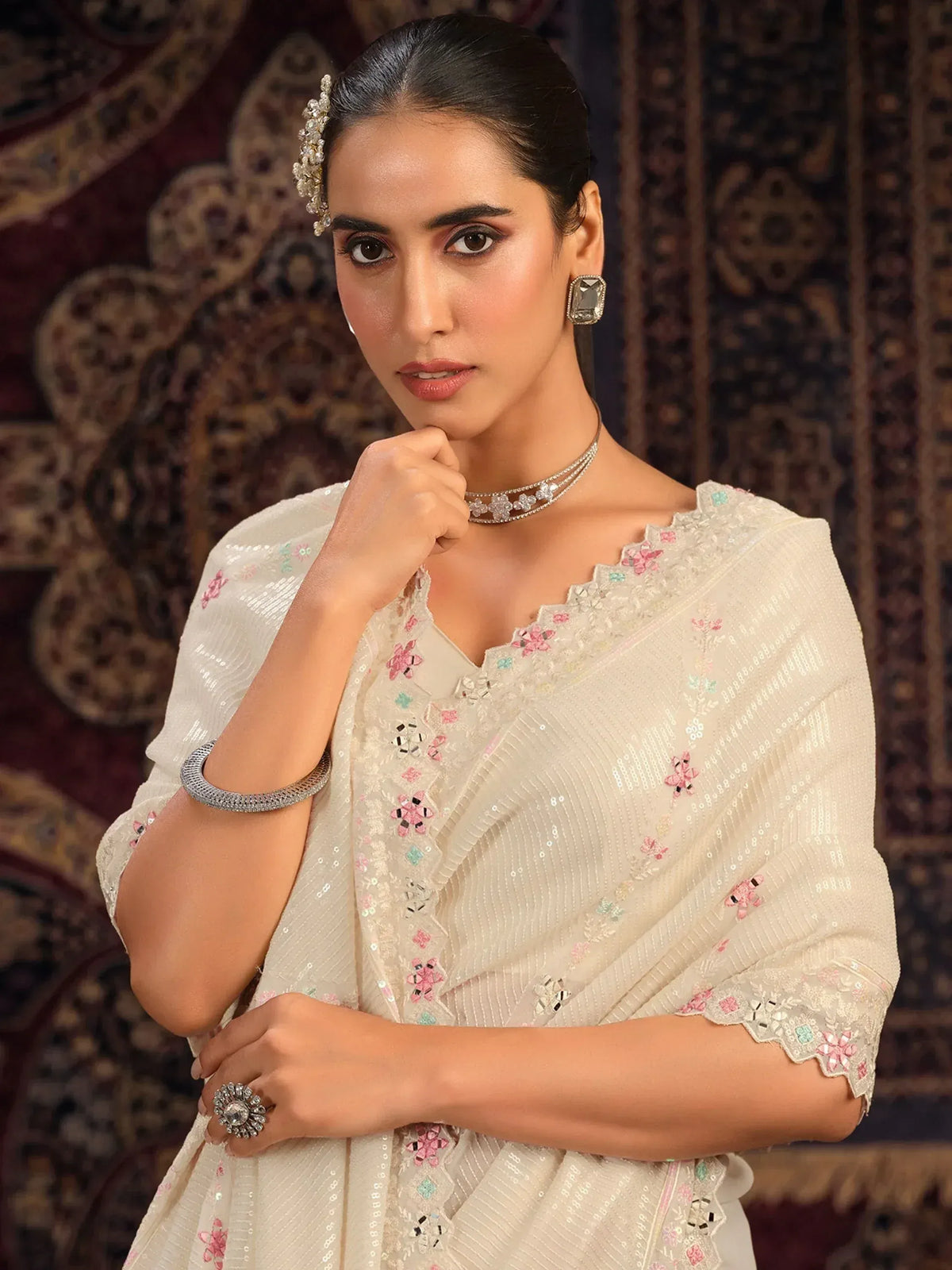 Elegant woman in ivory floral embroidered ethnic gown with statement jewelry, perfect for Indian occasions