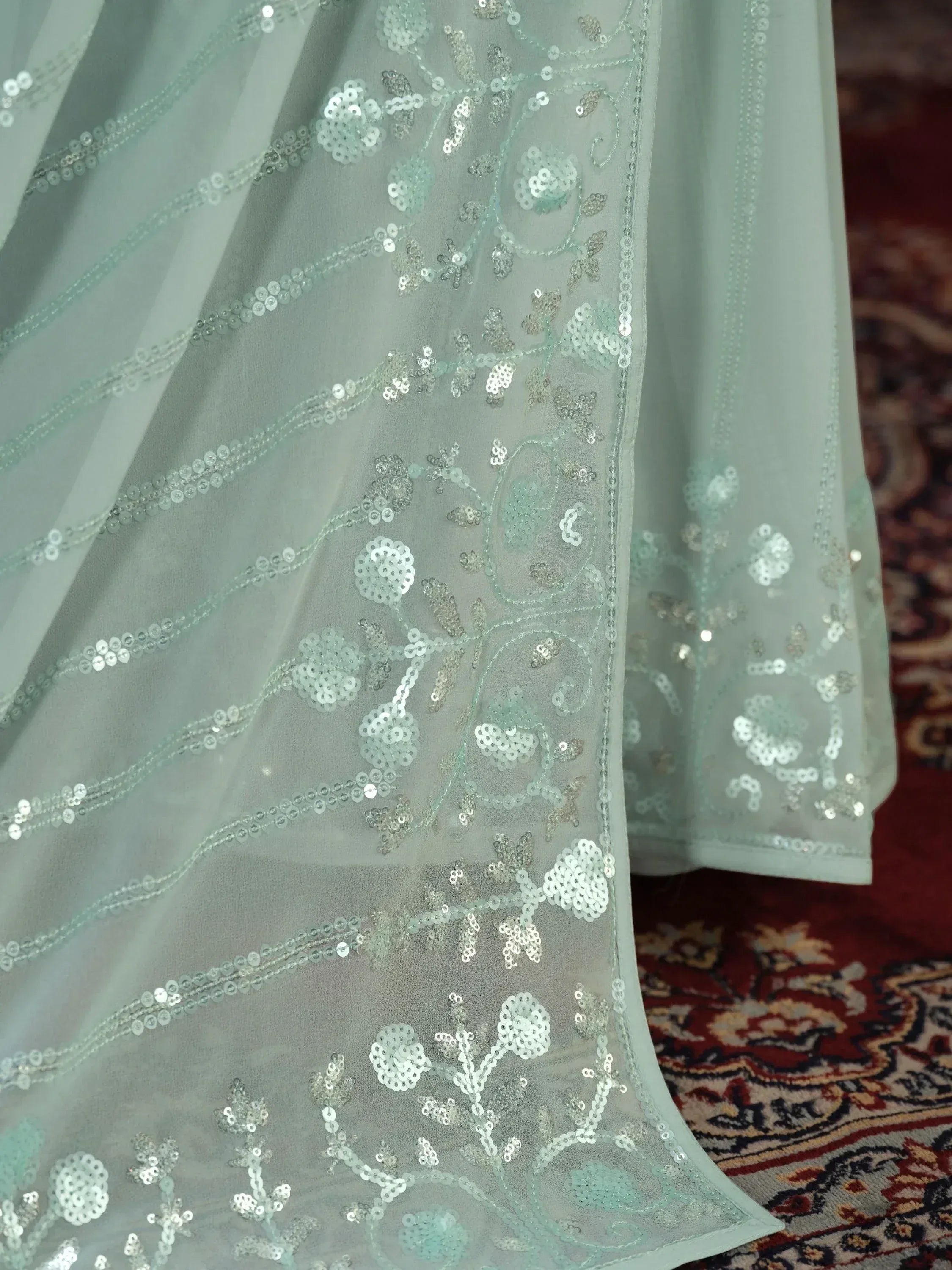 Mint green ethnic gown with silver sequin floral embroidery, sheer fabric, perfect for Indian weddings and parties.