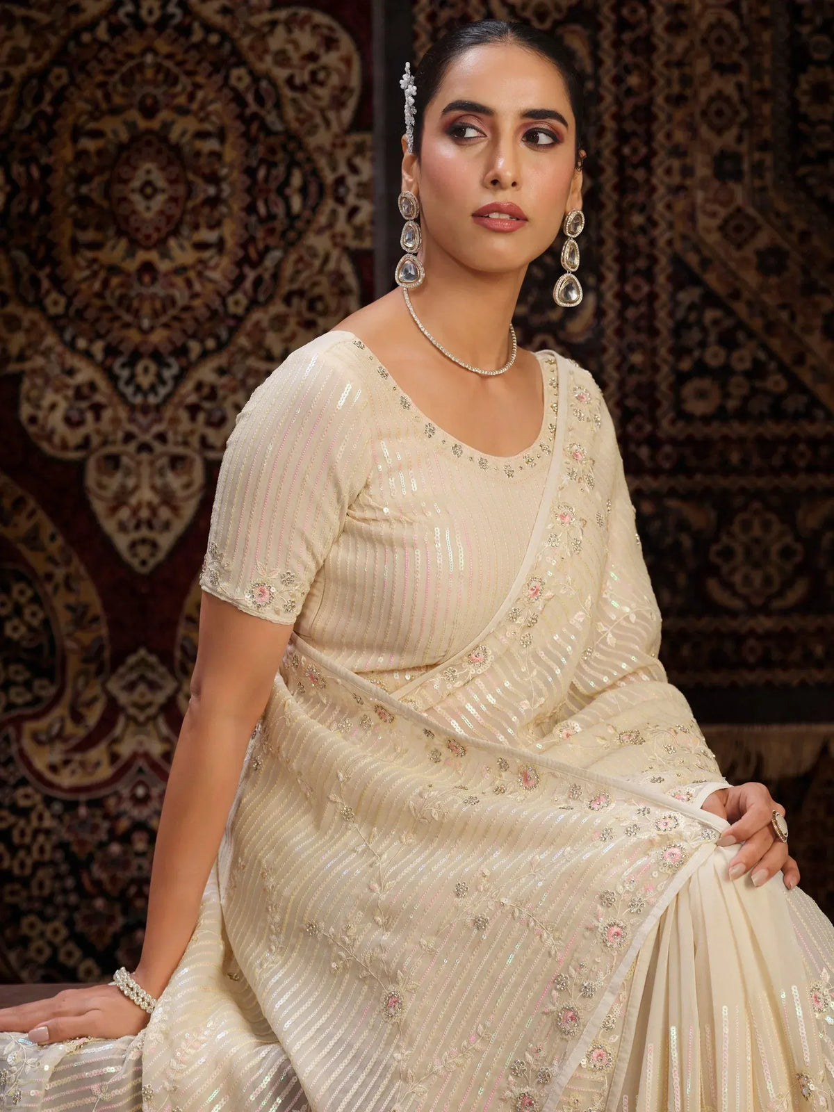 Elegant cream saree with sequin stripes and floral embroidery, perfect for Indian ethnic occasions.