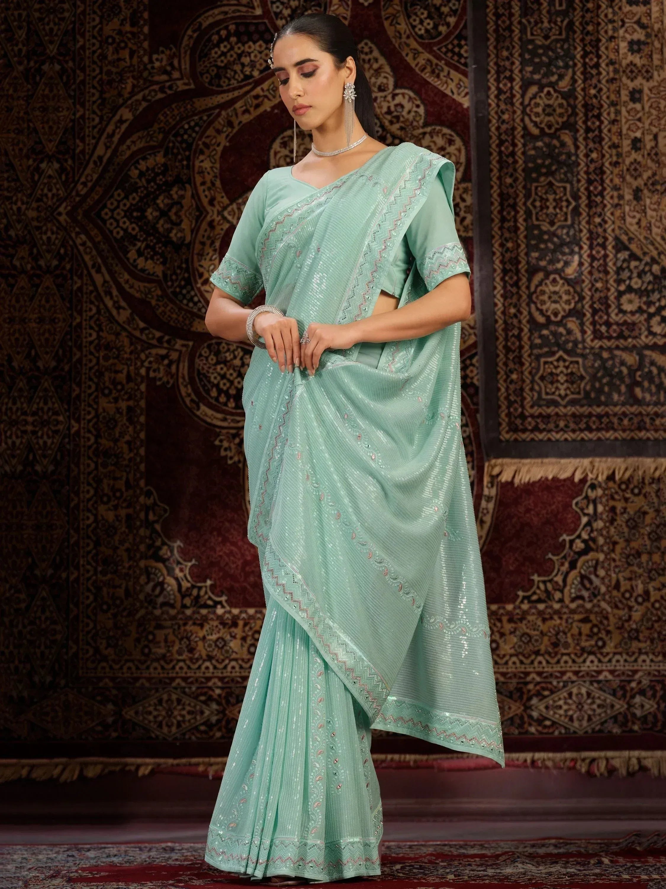 Mint green sequin saree with embroidered border, styled with matching blouse for ethnic occasions
