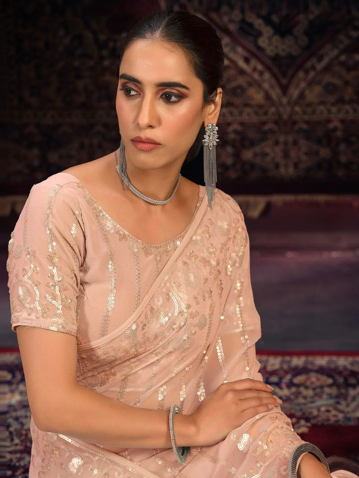 Elegant woman in blush pink sequin saree with designer jewelry, perfect for Indian ethnic occasions.