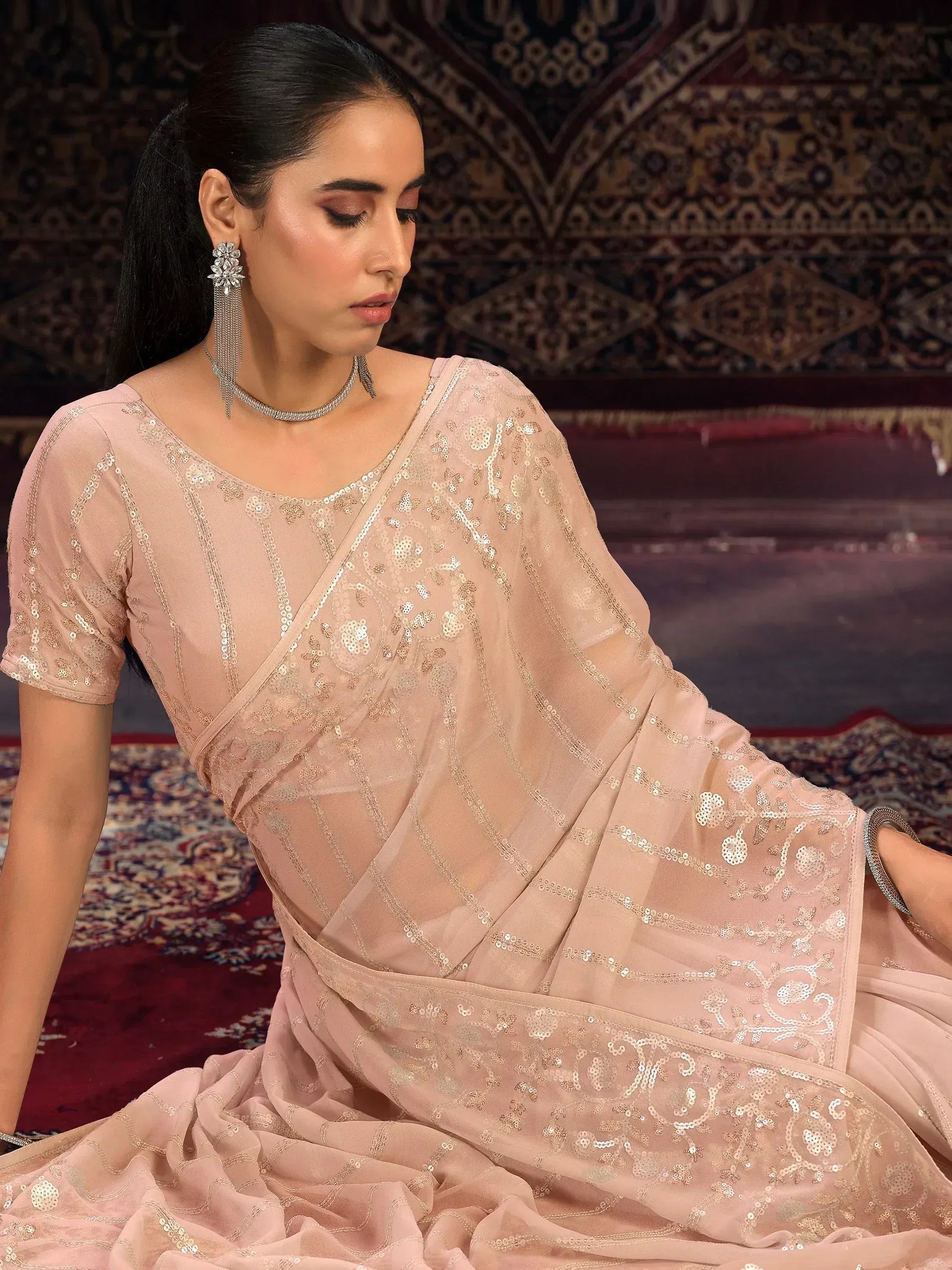 Elegant blush pink saree with sequin embroidery, styled with statement earrings and choker for festive occasions