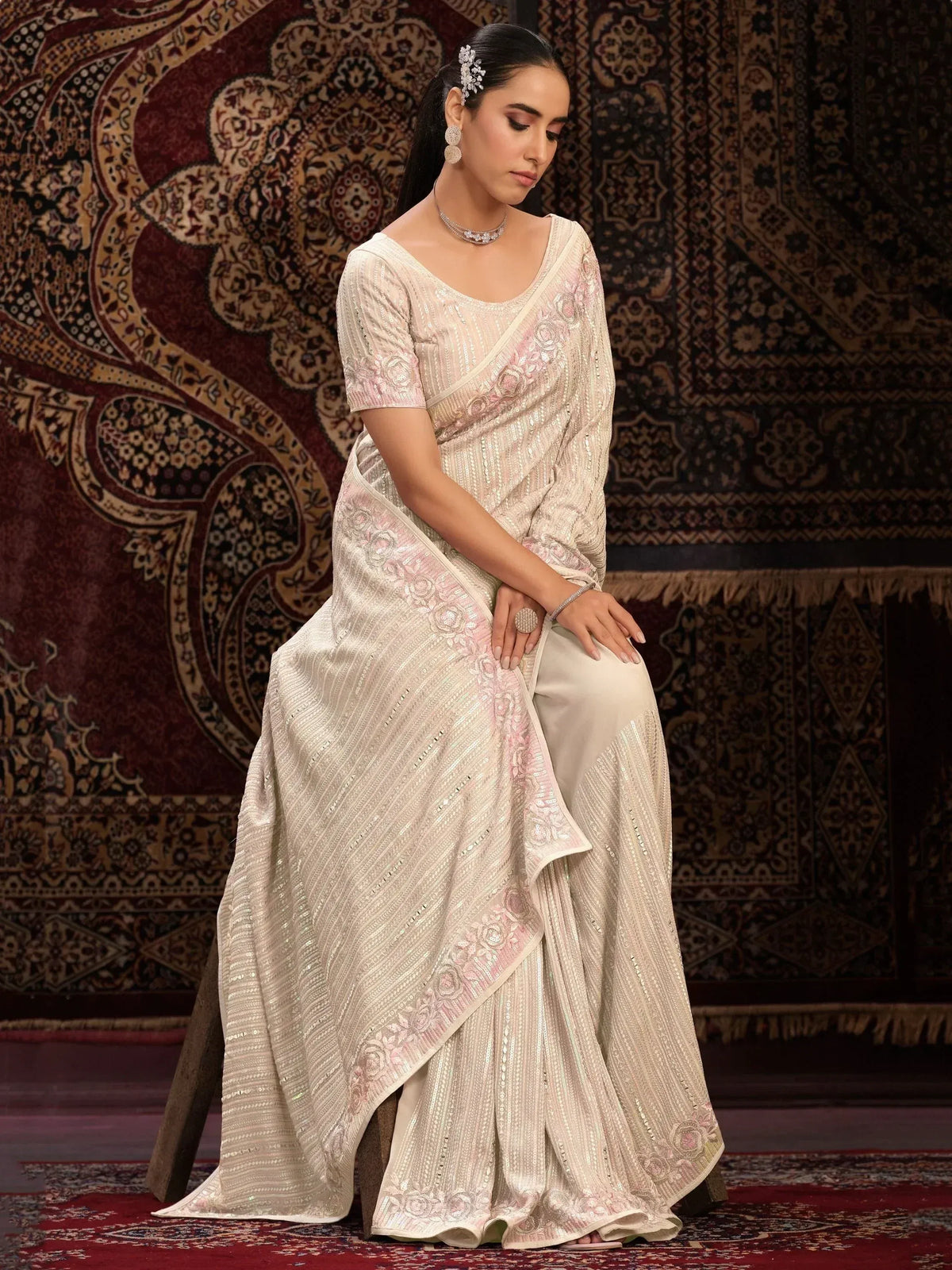 Elegant ivory saree with pink floral embroidery and sequin detailing, styled with matching blouse and jewelry