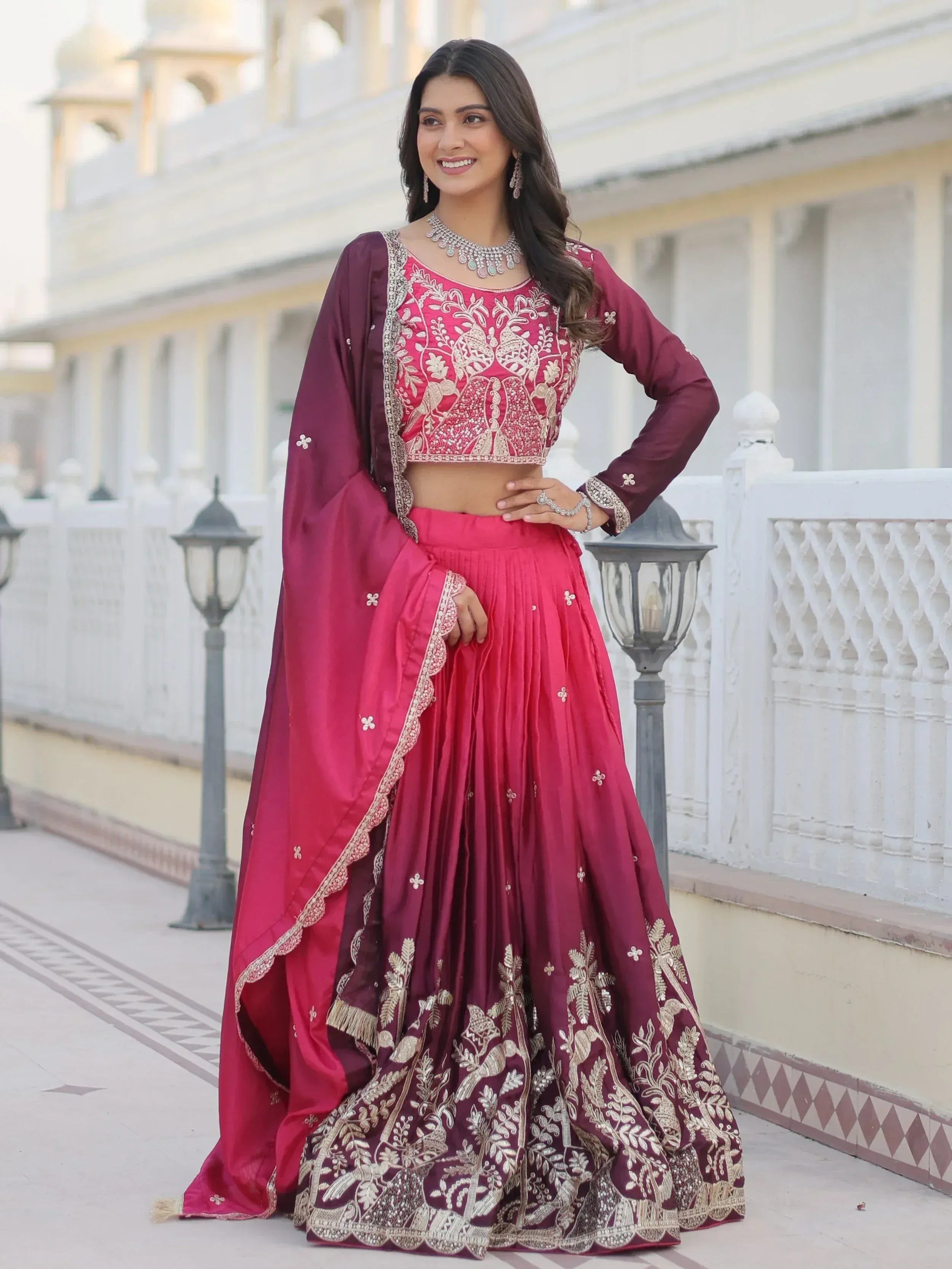 Woman in maroon and pink embroidered lehenga choli with gold detailing, perfect for Indian ethnic wear occasions.