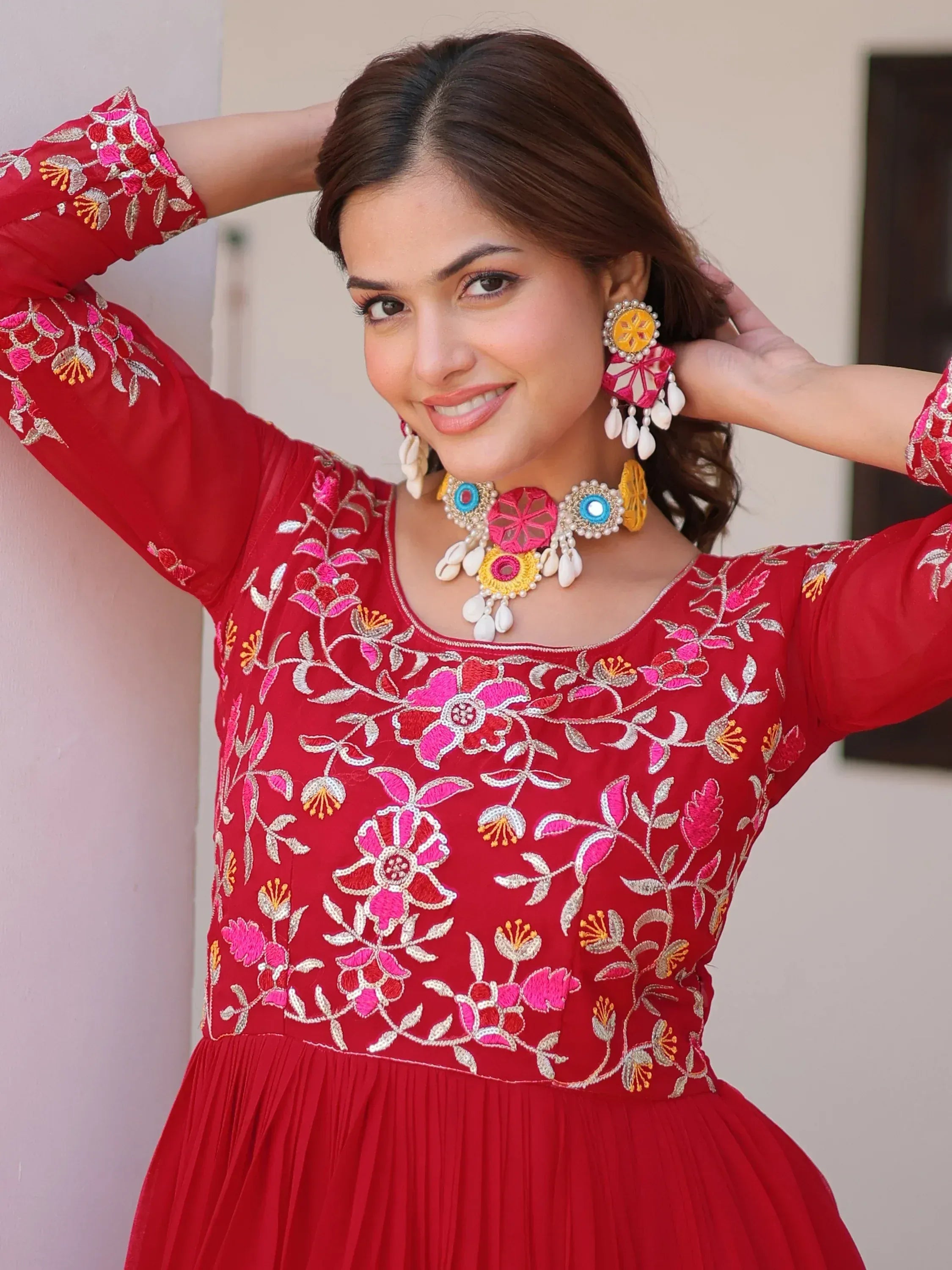 Red embroidered ethnic gown with floral design, paired with statement jewelry for festive occasions