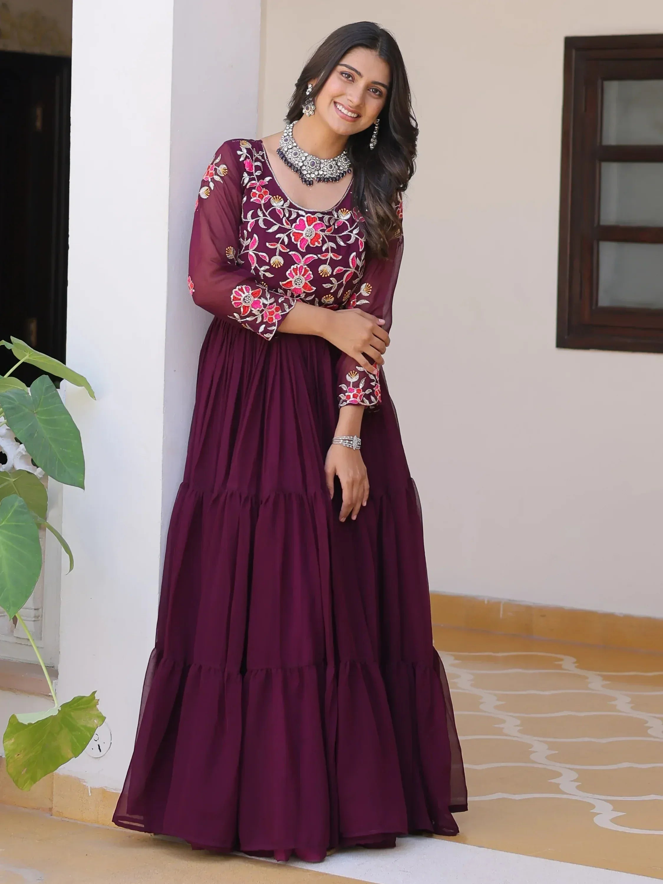 Woman in maroon embroidered ethnic gown with floral design, perfect for Indian occasions
