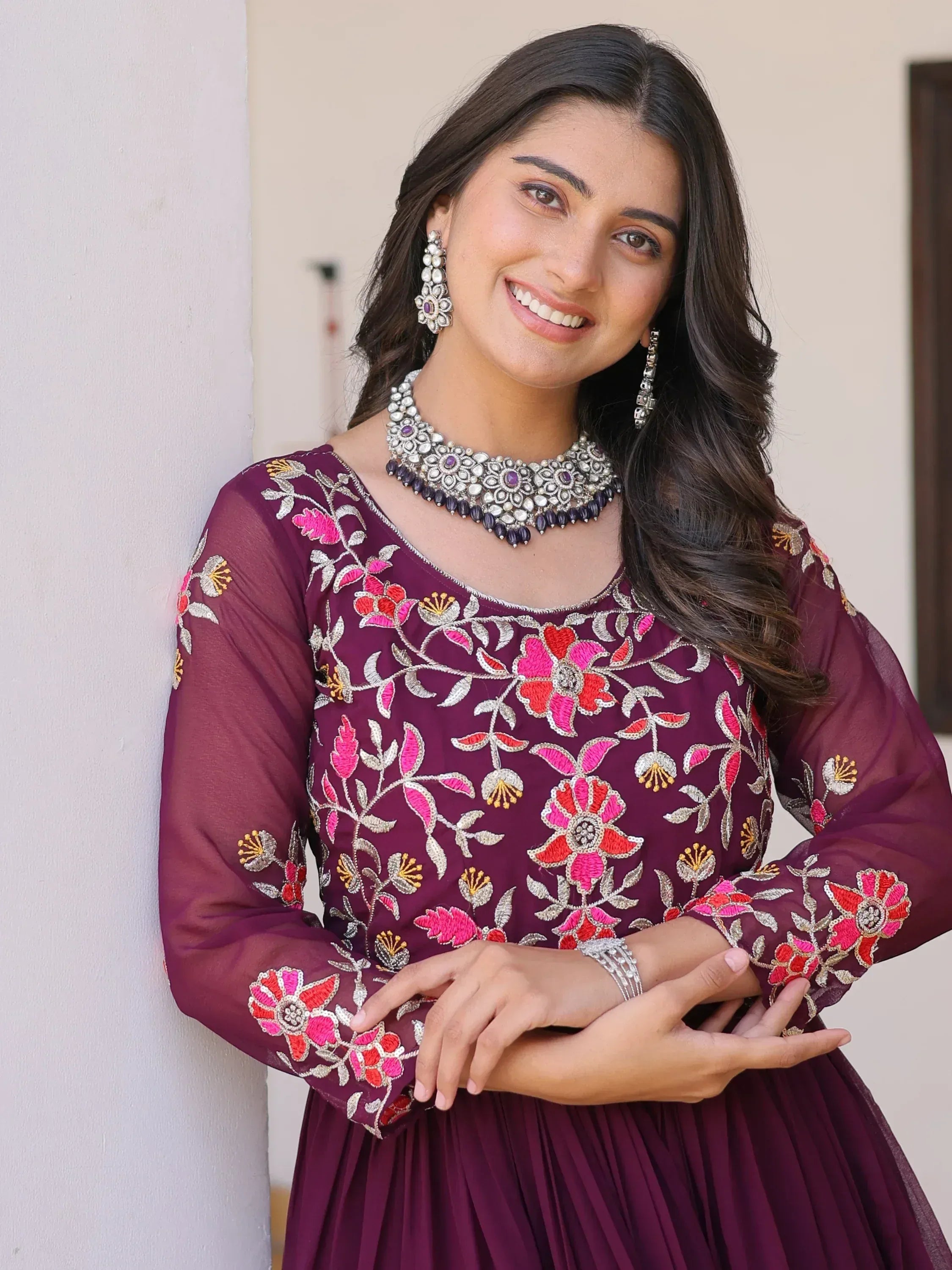 Woman in maroon floral embroidered ethnic gown with statement jewelry, perfect for Indian occasions