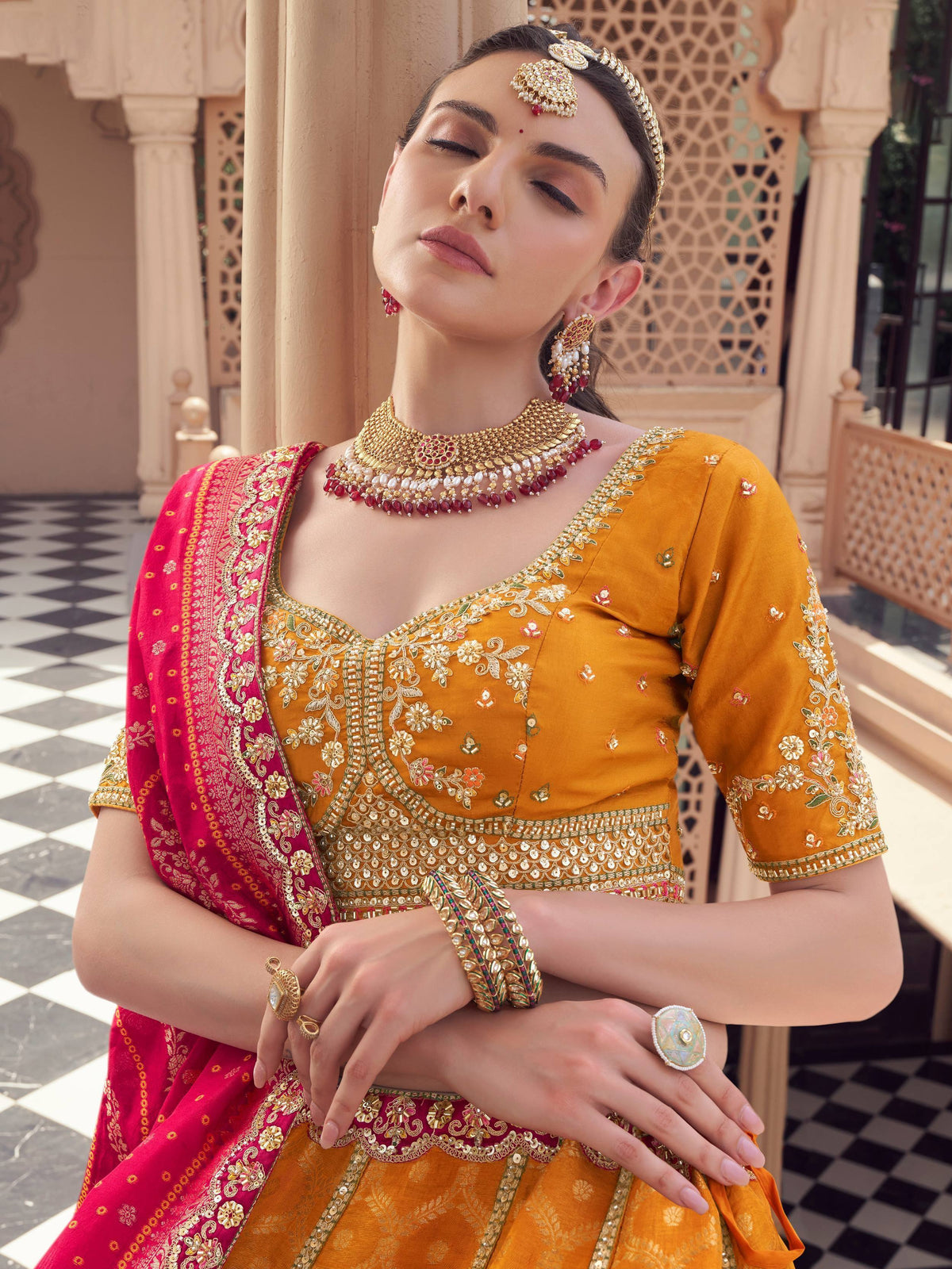 Woman in mustard yellow embroidered lehenga choli with red dupatta, traditional Indian ethnic wear