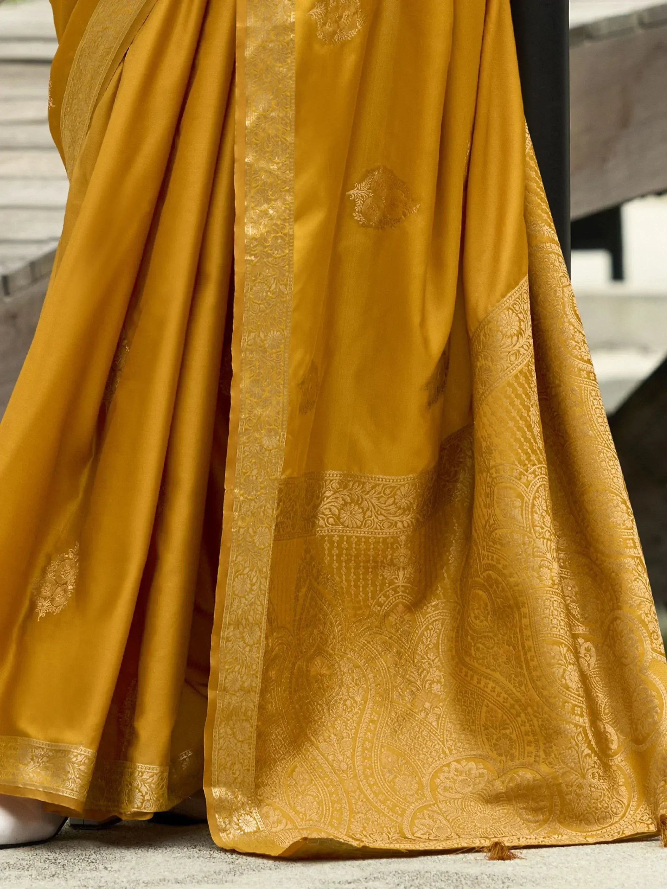 Mustard yellow designer saree with intricate gold paisley border and floral motifs, perfect for ethnic occasions.