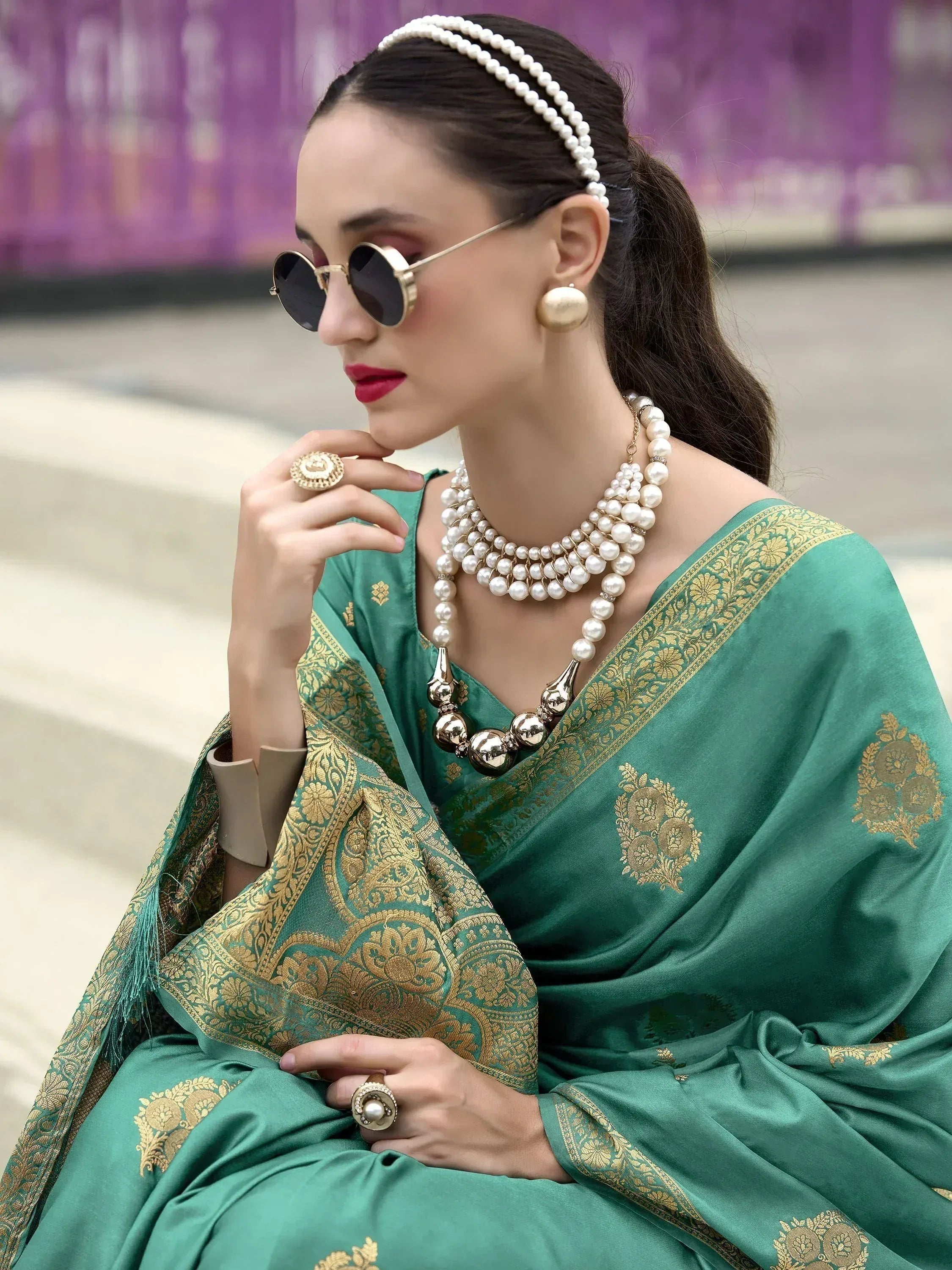 Woman in elegant green saree with gold embroidery, pearl jewelry, and sunglasses for Indian ethnic wear