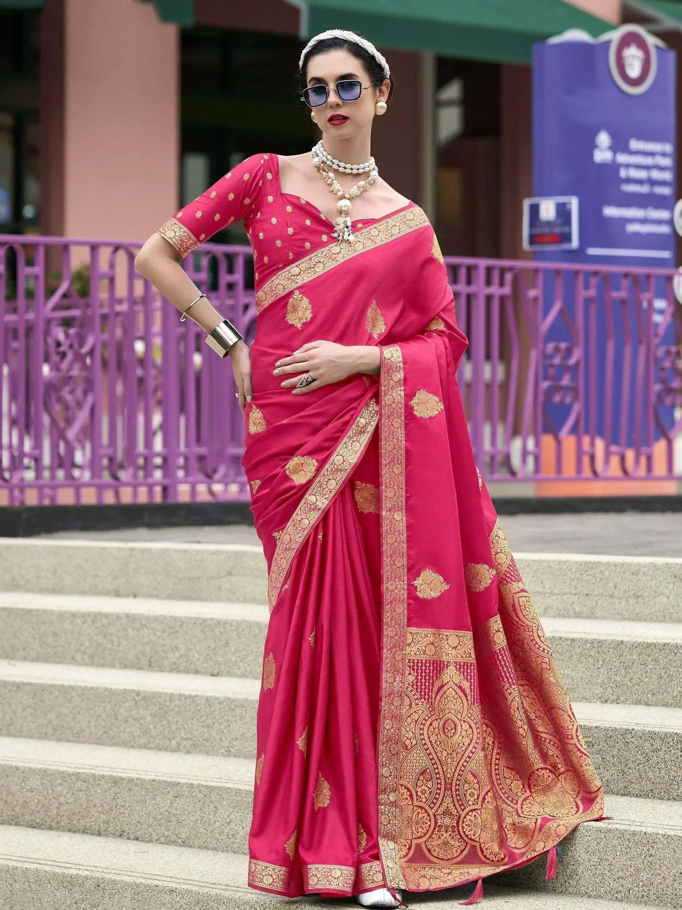 Woman in vibrant pink designer saree with gold embroidery, styled for ethnic occasions