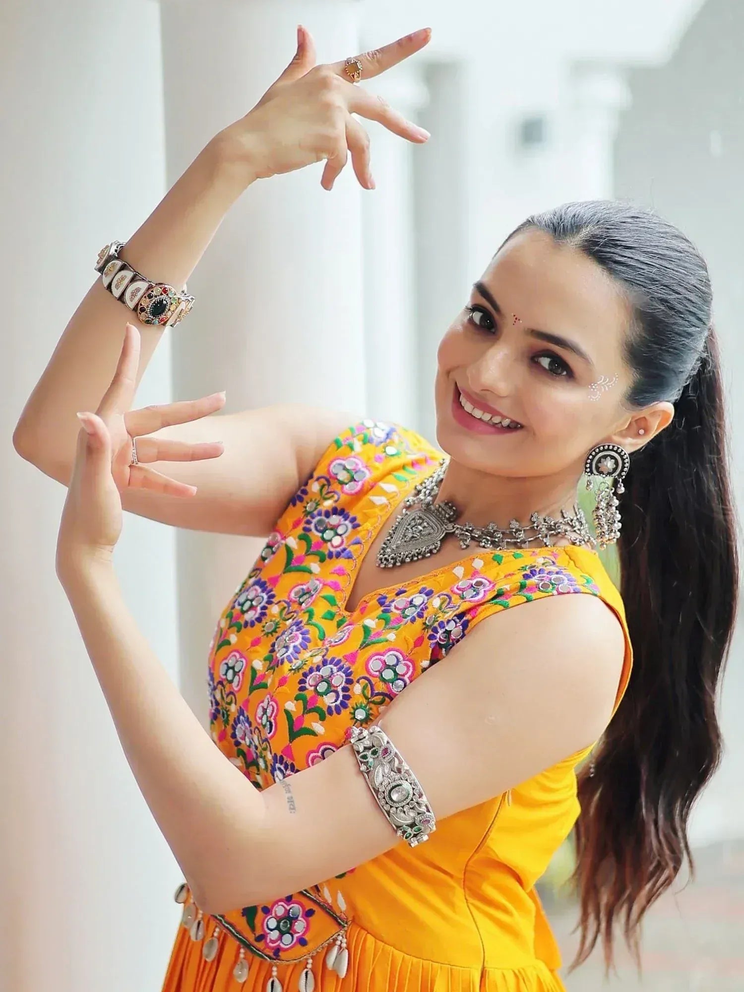Woman in vibrant yellow embroidered ethnic gown with traditional jewelry, posing gracefully