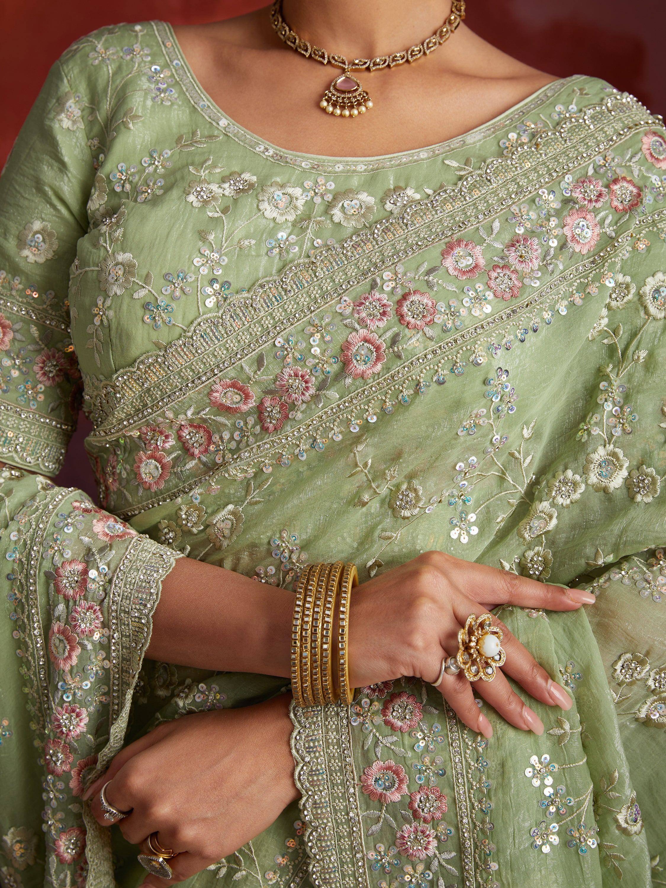 Mint green embroidered ethnic gown with floral sequin detailing and gold jewelry, perfect for Indian occasions.