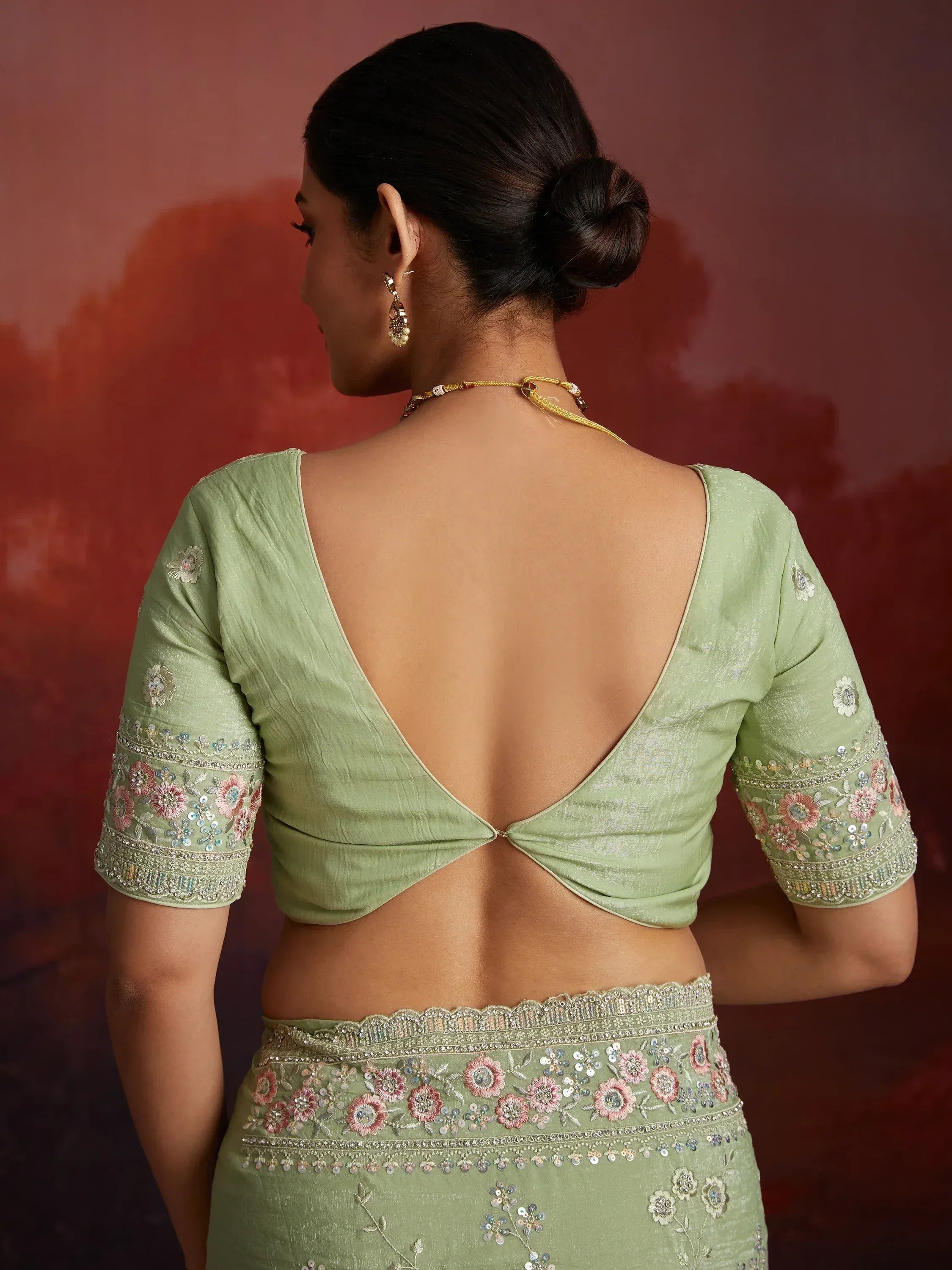 Light green embroidered lehenga choli with open back blouse and floral detailing, perfect for Indian ethnic wear.