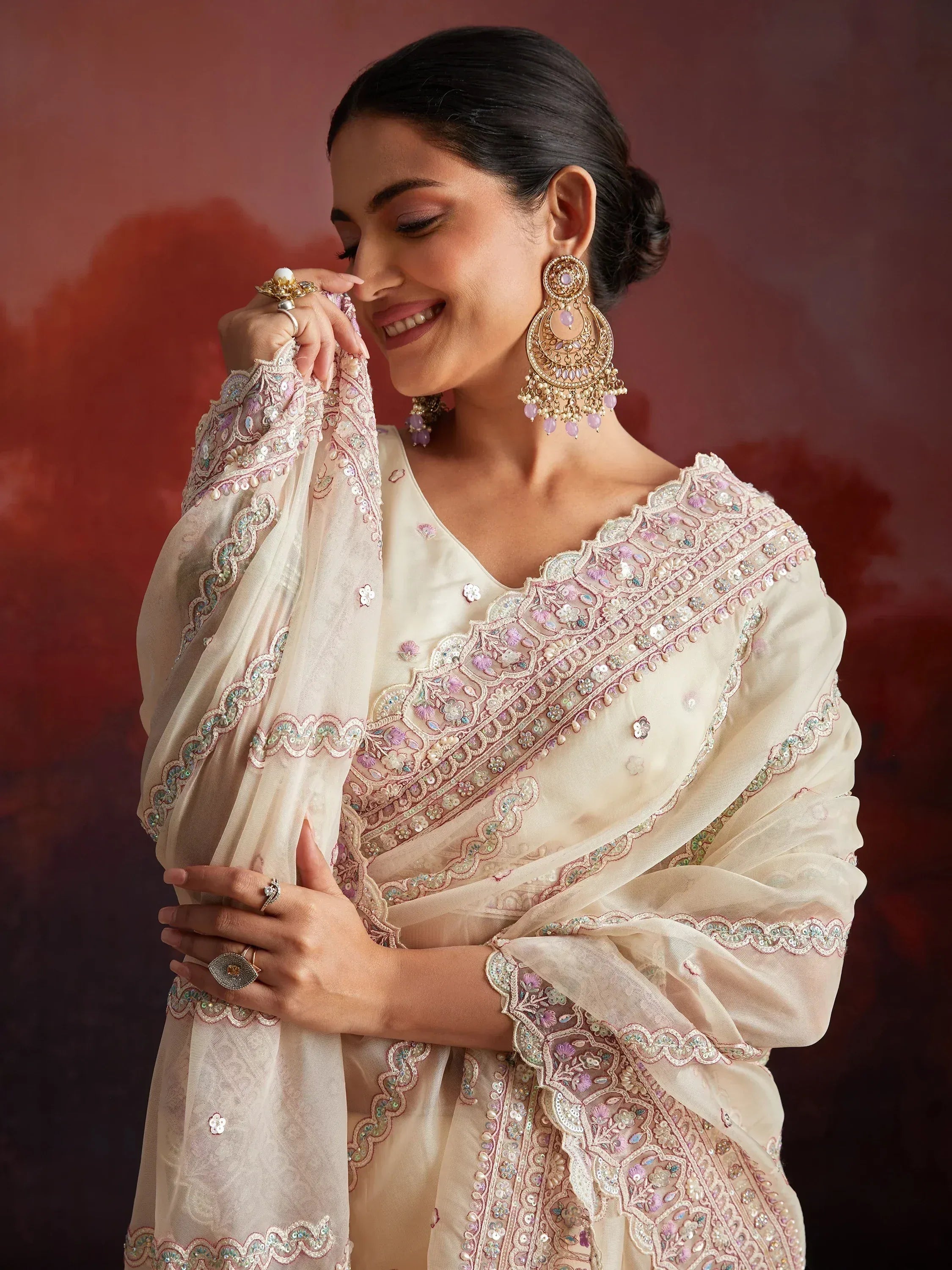 Elegant cream salwar kameez with pink floral embroidery and matching dupatta, styled with statement earrings.