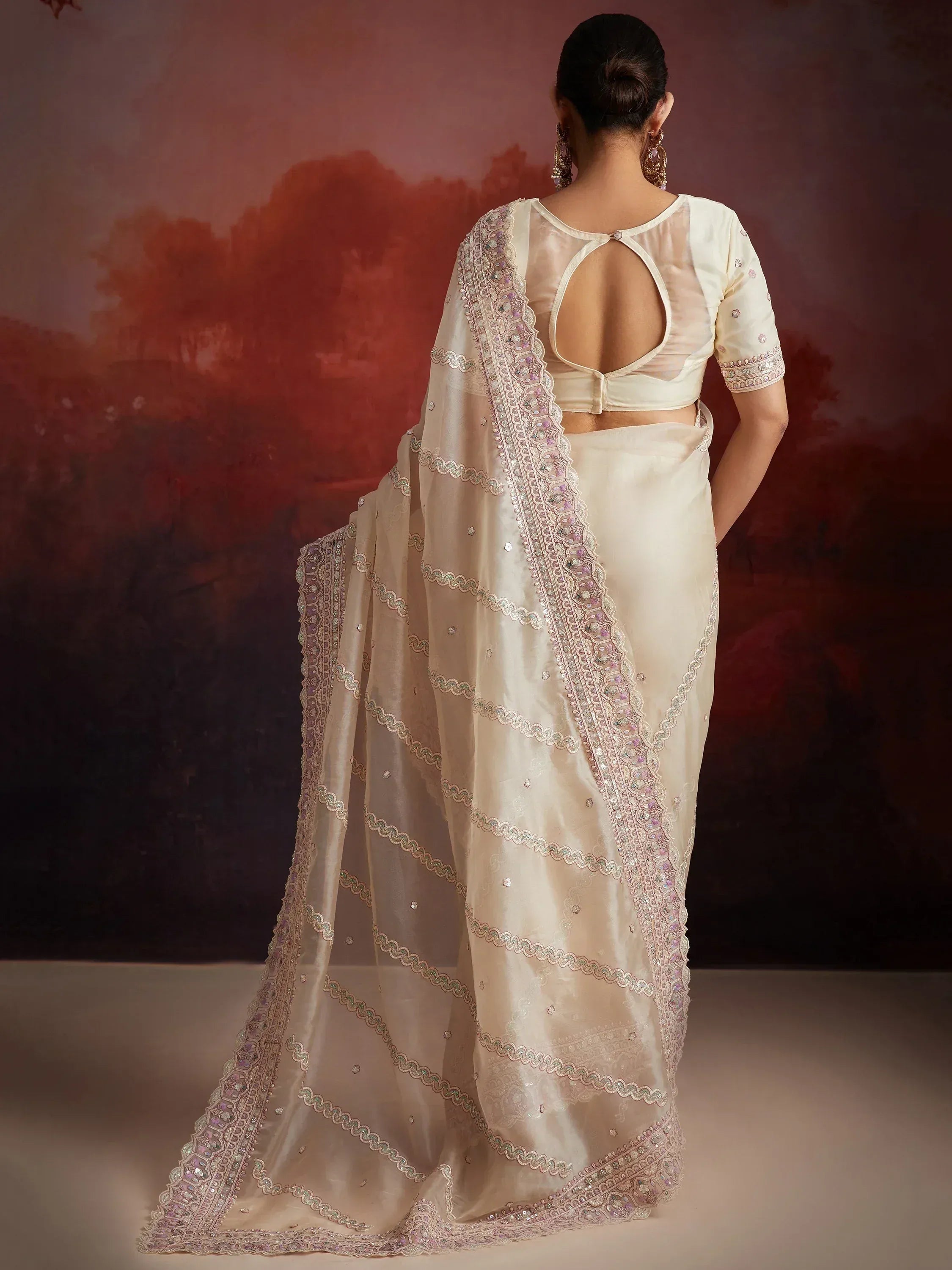 Cream designer saree with intricate embroidery and sheer blouse, perfect for Indian ethnic wear occasions.