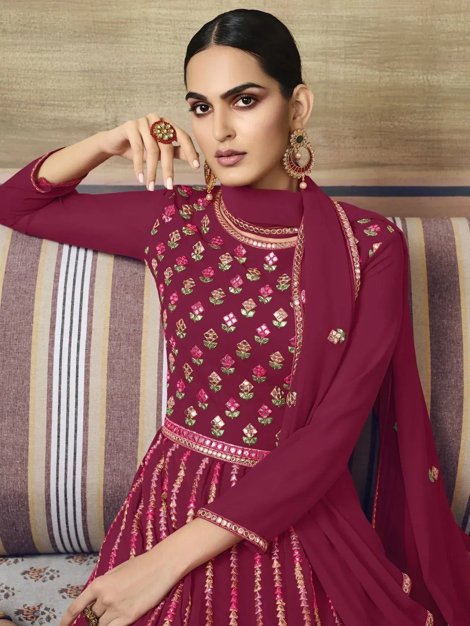 Maroon embroidered anarkali suit with floral motifs and mirror work, paired with statement jewelry