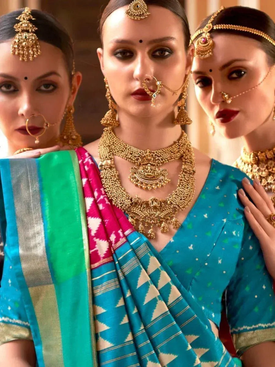 Three women in vibrant Indian sarees with gold jewelry and traditional nose rings, showcasing ethnic fashion.